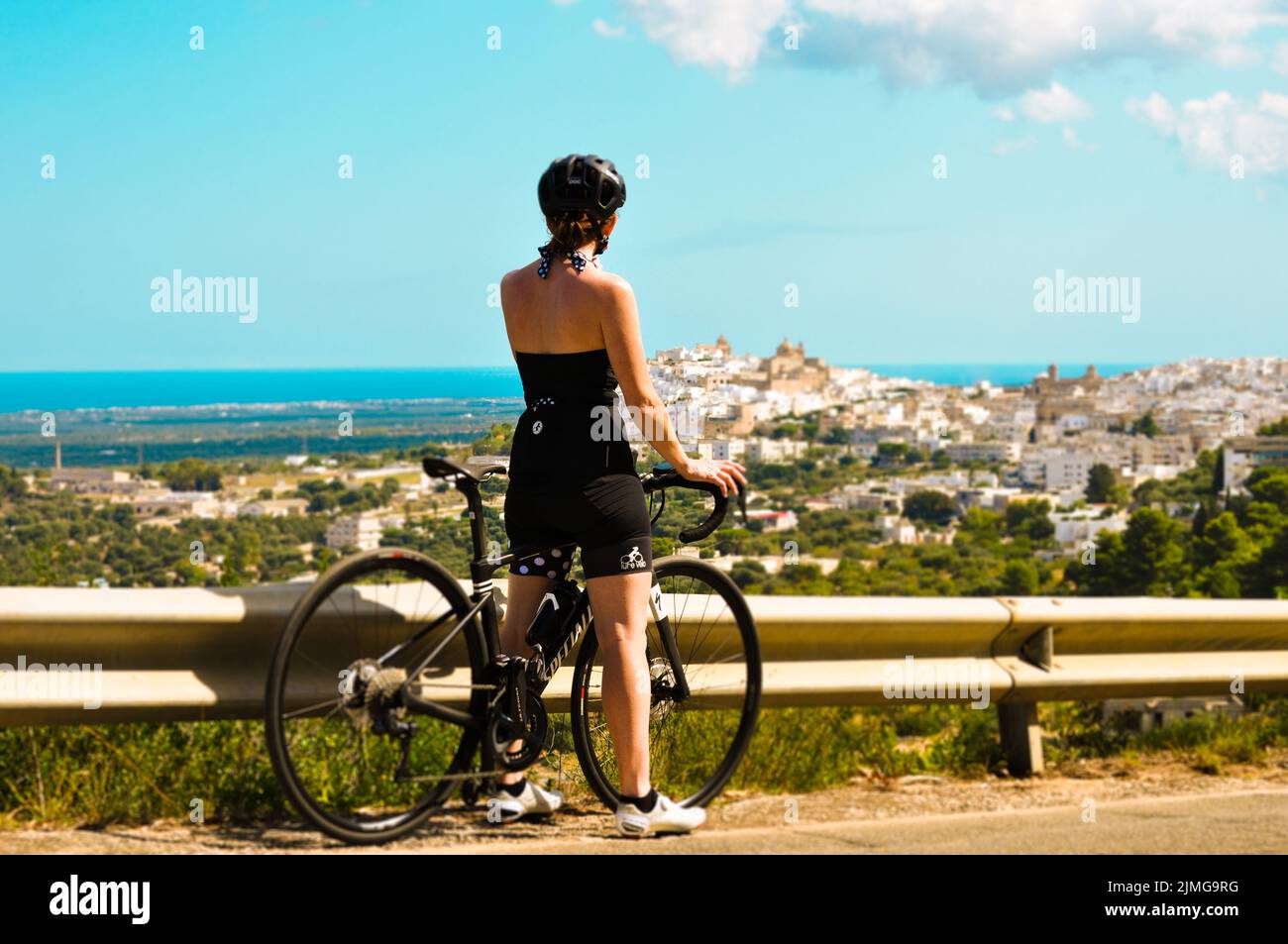 Radfahrer auf dem Rennrad mit Blick auf die Stadt. Sommerurlaub Stockfoto