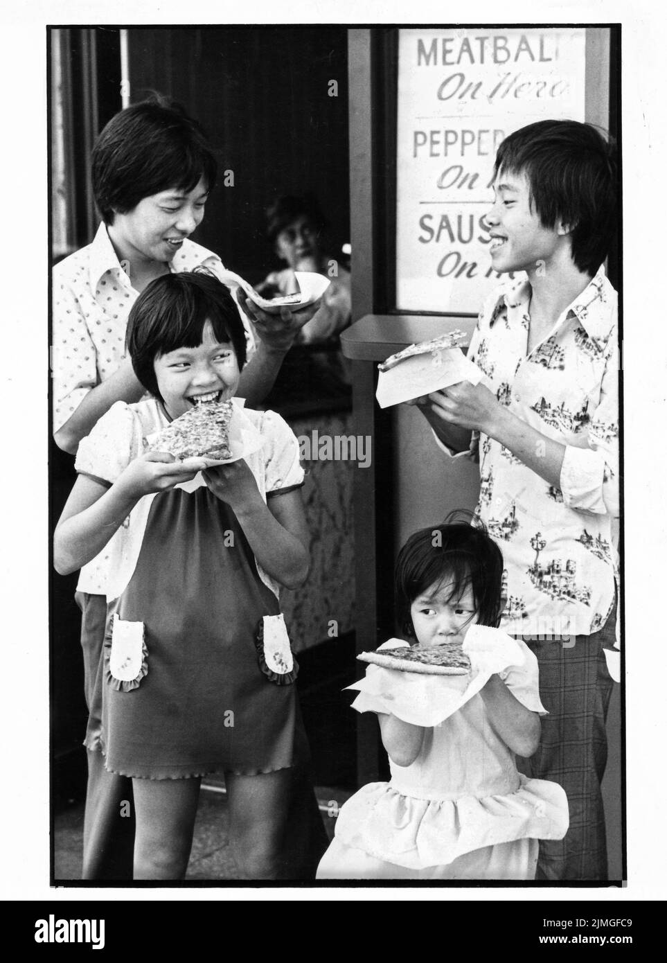 4 vietnamesische Bootsleute siedeln sich in Queens, New York, an und akklimatisieren sich bei Pizzaschnitten an die neue Kultur. 1980 in NYC. Stockfoto