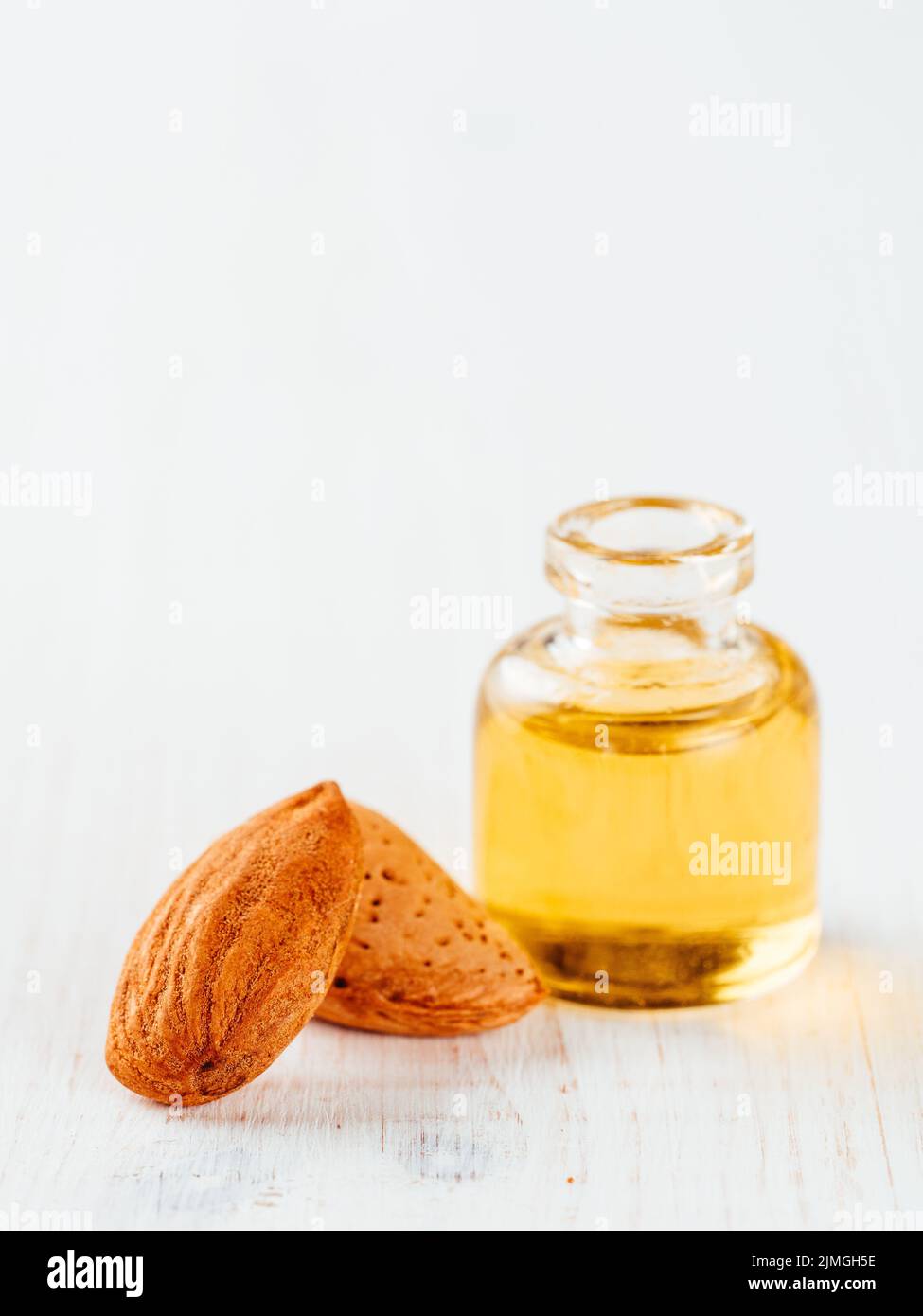 Flasche Mandelöl und Mandeln auf weißem Hintergrund Stockfoto
