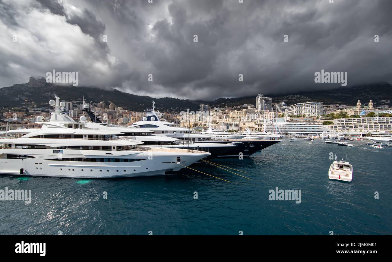 Viele riesige Yachten sind im Hafen von Monaco bei Sturmwetter, Berg ist im Hintergrund, Hochglanz-Board des Motorbootes, Megayach Stockfoto