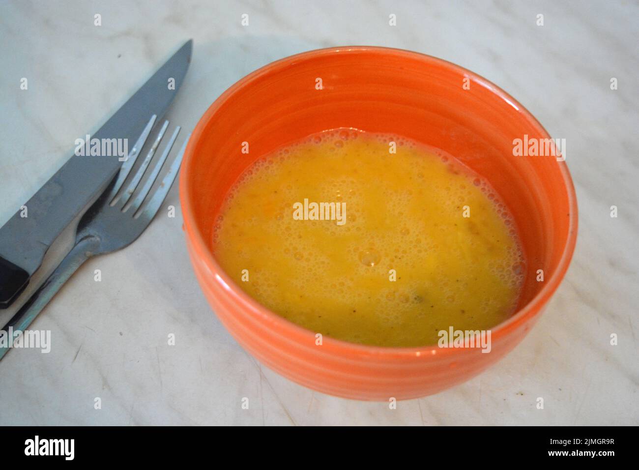 Gesundes Essen, Rühreier in einen orangefarbenen Tonteller gegossen. Stockfoto