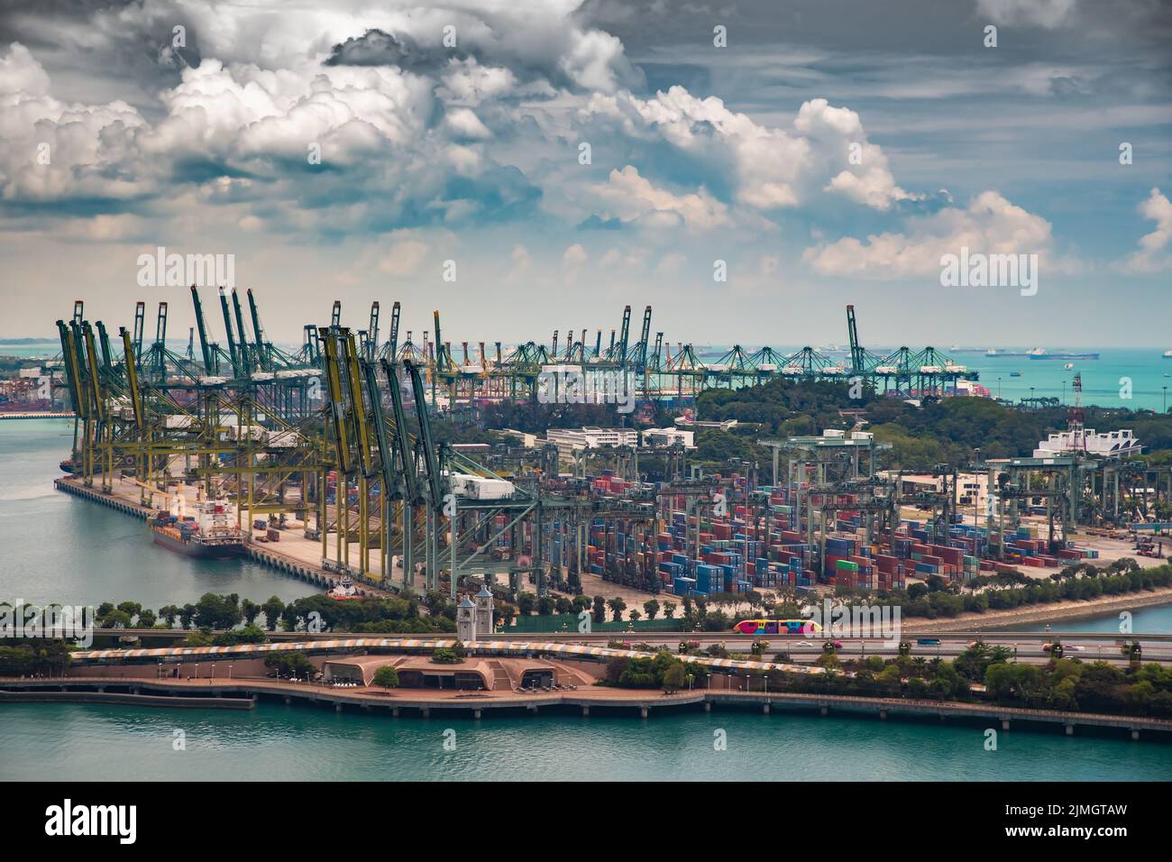 Der riesige verkehrsreichste Logistikhafen in Singapur, viele Krane, um Container zu bewegen, riesige Frachtschiffe im Hintergrund, Wolkenkratzer Stockfoto