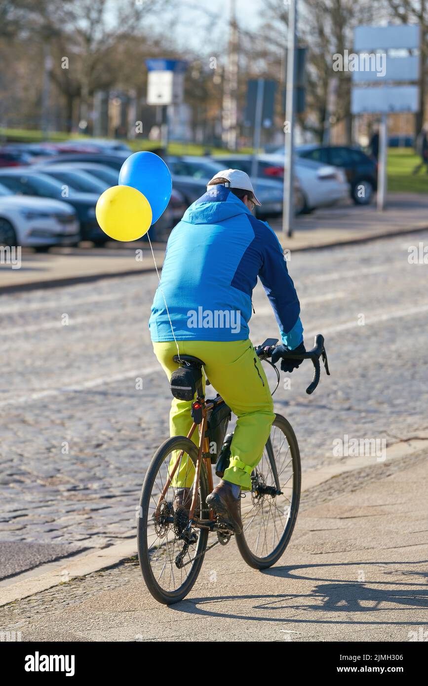 Ein Radfahrer, der die Farben der Ukraine trägt, auf dem Weg zu einer Demonstration gegen die Invasion Stockfoto