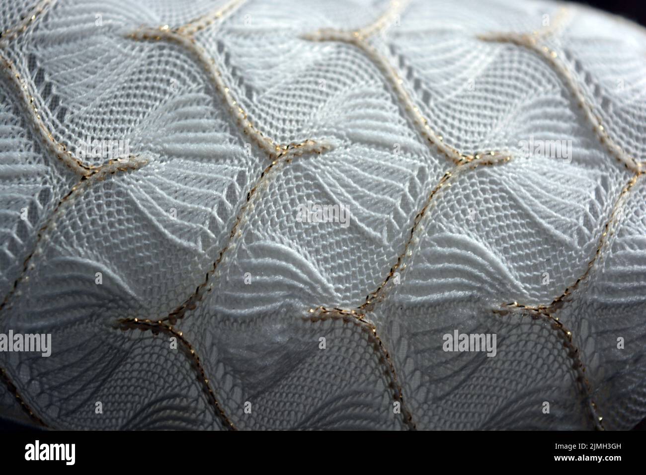 Schöner weißer Webstoff mit einem faszinierenden Muster aus dichten weißen Fäden und feinen goldenen Fäden. Schöne dünne Gossamer Weberei, luxuriös. Stockfoto