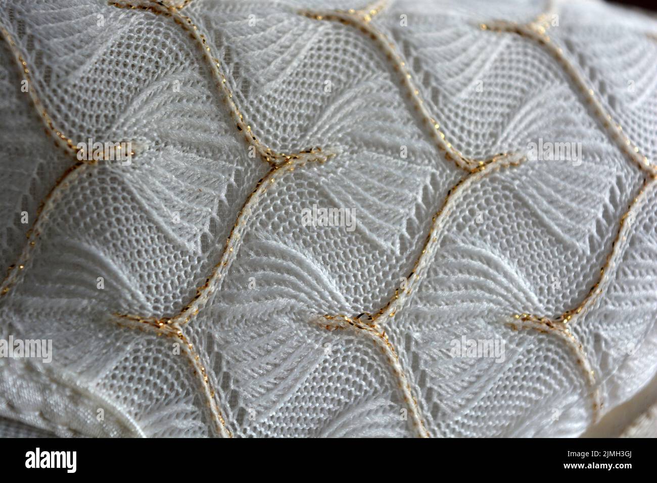 Schöner weißer Webstoff mit einem faszinierenden Muster aus dichten weißen Fäden und feinen goldenen Fäden. Schöne dünne Gossamer Weberei, luxuriös. Stockfoto