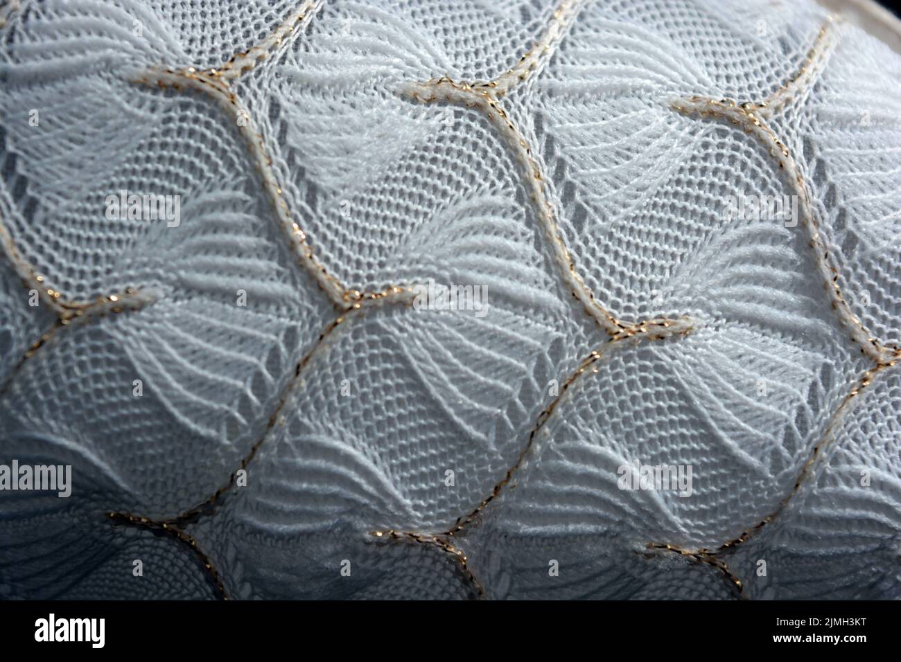 Schöner weißer Webstoff mit einem faszinierenden Muster aus dichten weißen Fäden und feinen goldenen Fäden. Schöne dünne Gossamer Weberei, luxuriös. Stockfoto