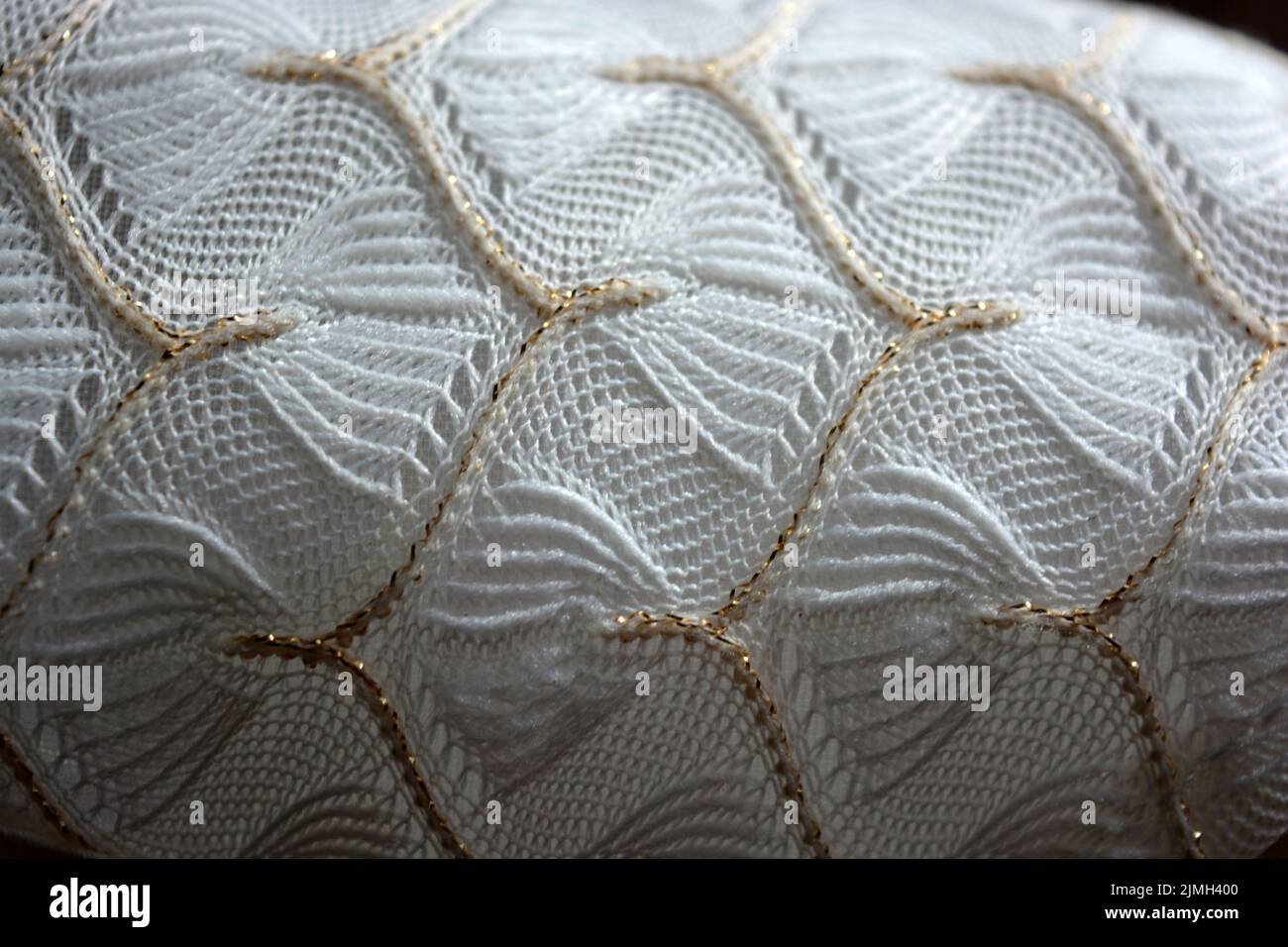 Schöner weißer Webstoff mit einem faszinierenden Muster aus dichten weißen Fäden und feinen goldenen Fäden. Schöne dünne Gossamer Weberei, luxuriös. Stockfoto