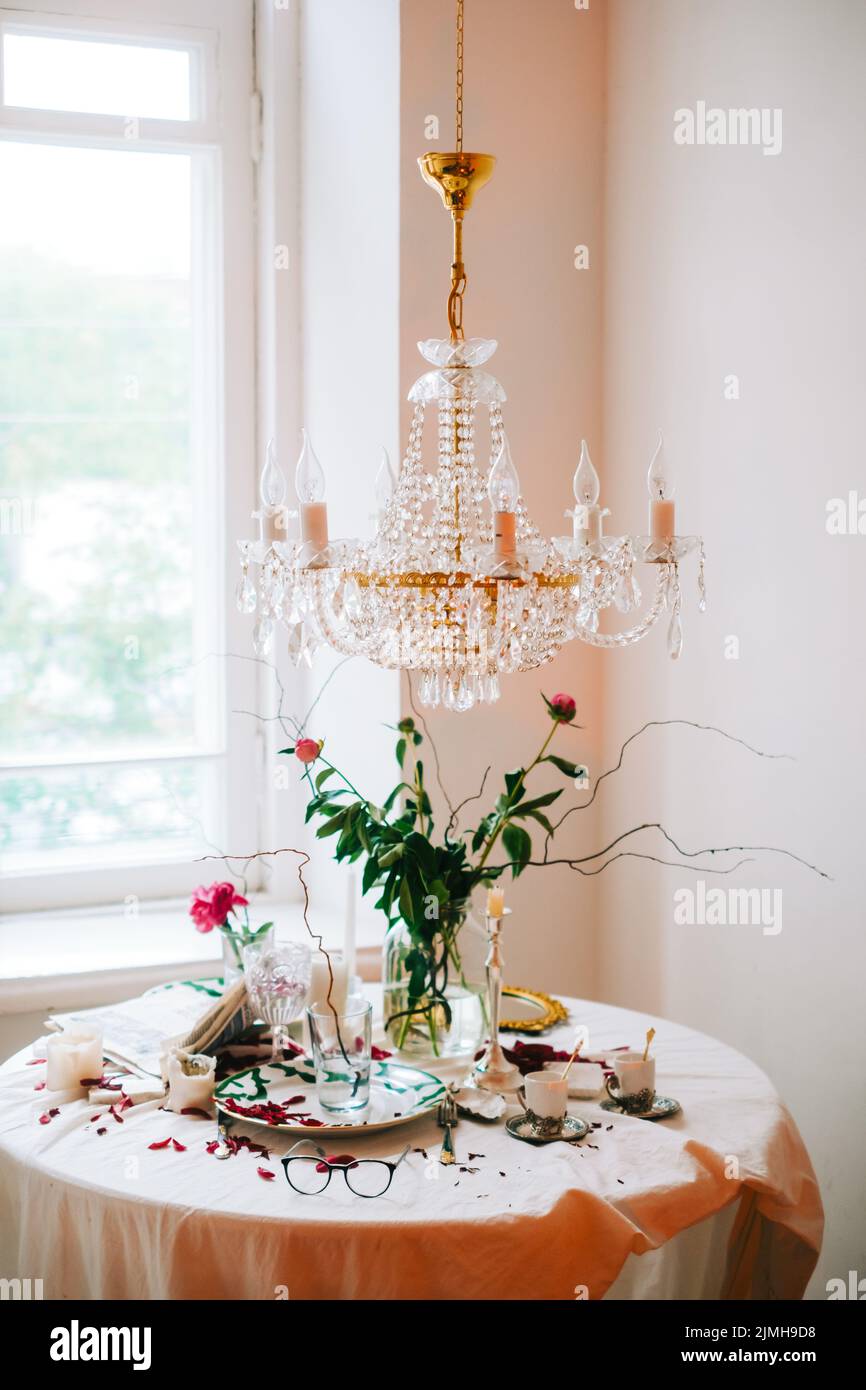 Innenraum des hellen Wohnzimmers mit Kronleuchter und Tisch mit Blumen. Stockfoto