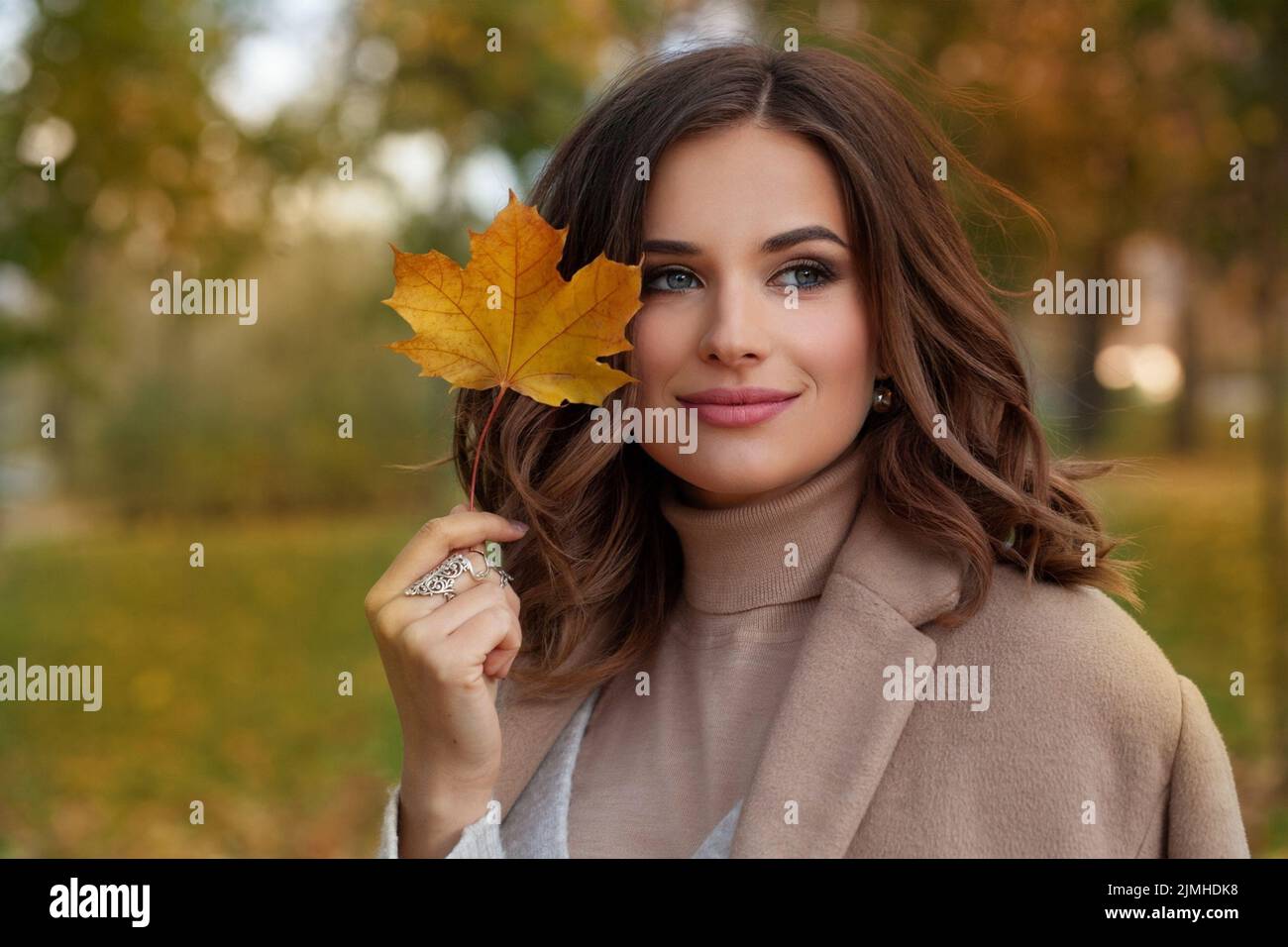 Glückliche Herbst Frau mit Fall gelb Ahornblatt Porträt. Schönes Modell mit lockiger Frisur. Stockfoto