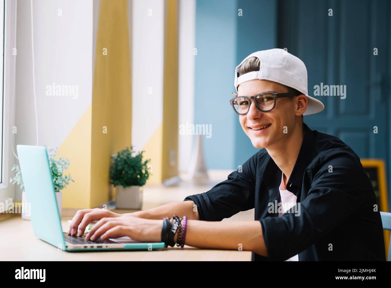 Lächelnder Jüngling mit Gadget im Klassenzimmer Stockfoto