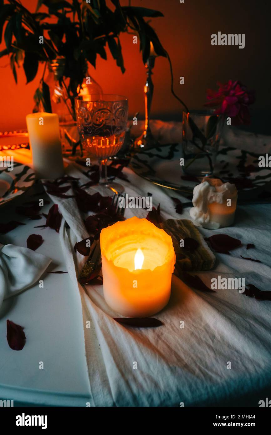 Tisch mit Kerzenständer und Blumenstrauß im Dunkeln. Stockfoto