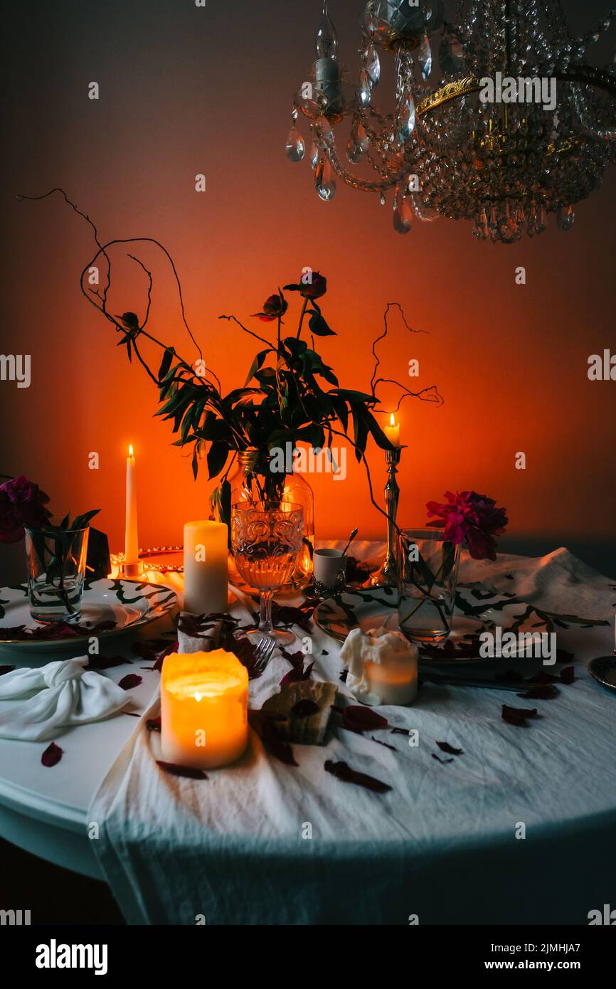 Tisch mit Kerzenständer und Blumenstrauß im Dunkeln. Stockfoto