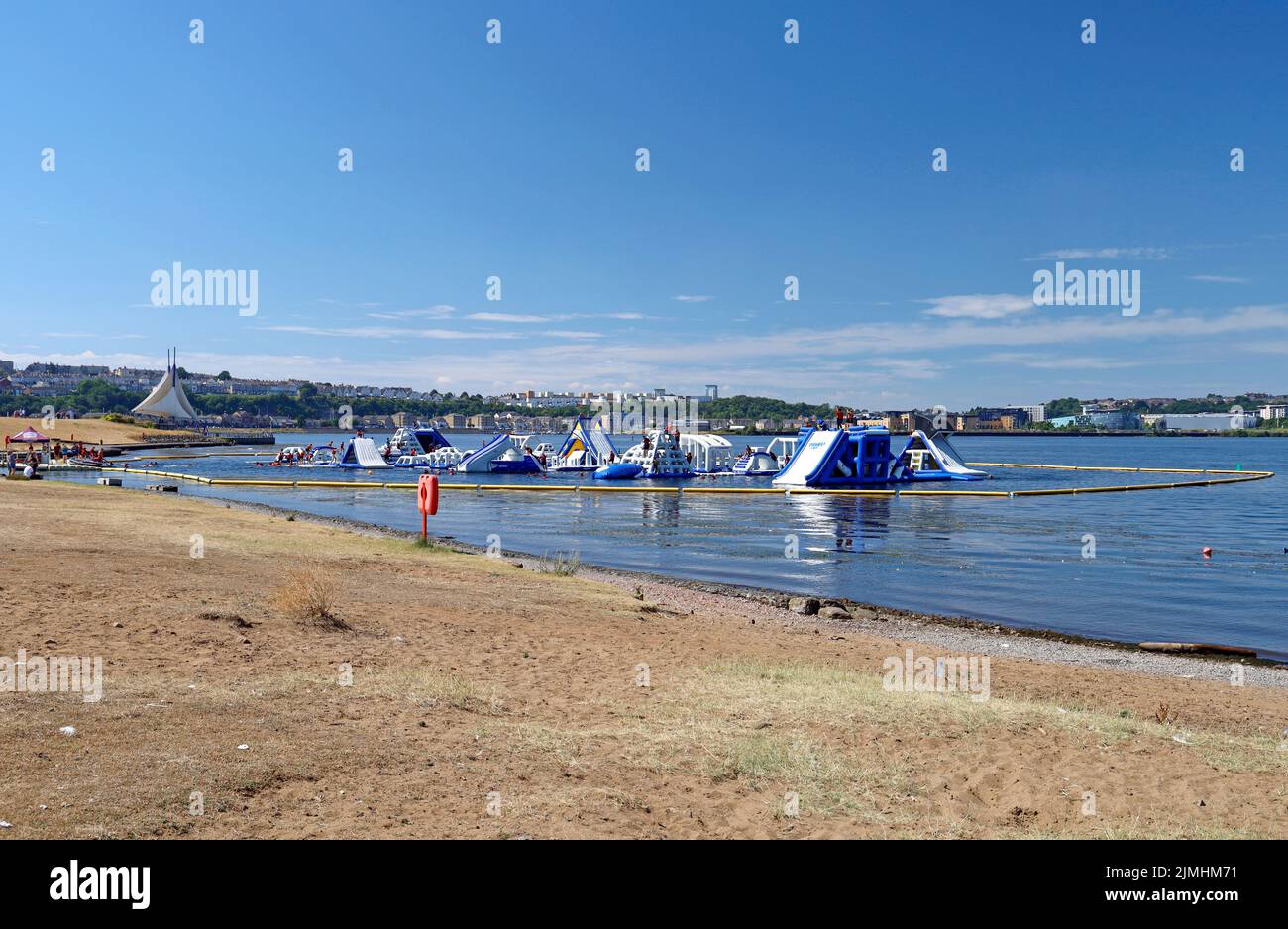 Cardiff Aqua Park aufblasbarer Hindernisparcours und lustige Wasserspielanlage. Cardiff Bay. Blick auf Cardiff Barrage. August 2022. Sommer Stockfoto