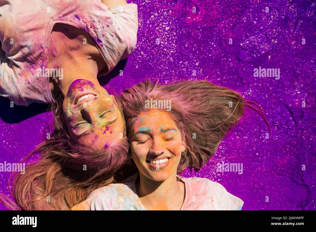 Junge Frauen mit holi Puder liegen lila Farbe bedeckt Stockfoto