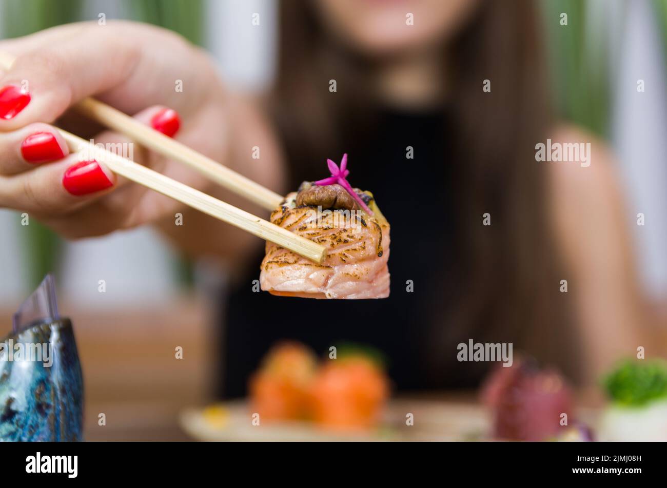 Frau, die leckeres Sushi isst, Nahaufnahme von Essstäbchen. Stockfoto