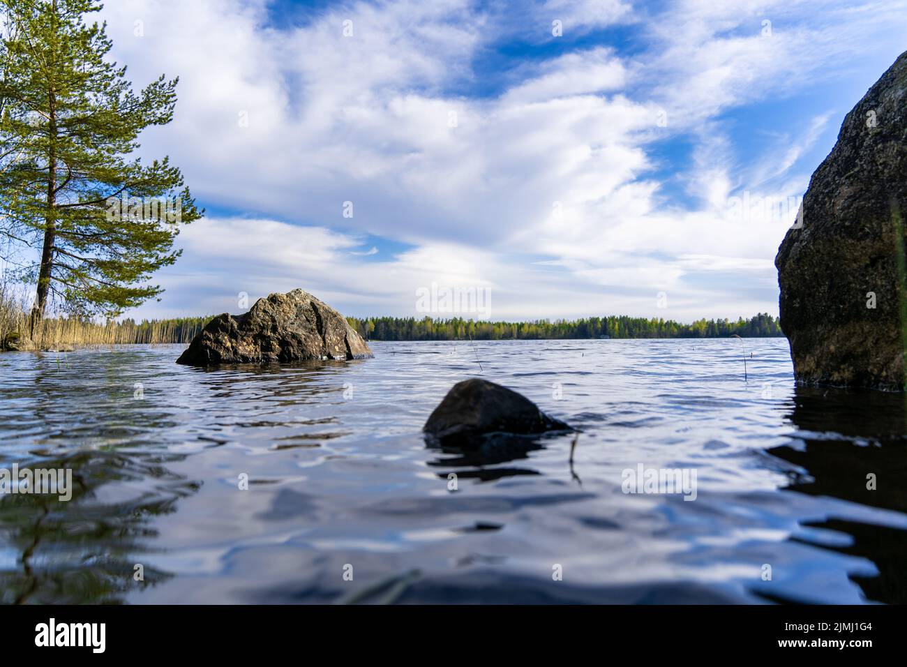 Ein klarer See mit Felsen und Bäumen unter blauem Himmel Stockfoto