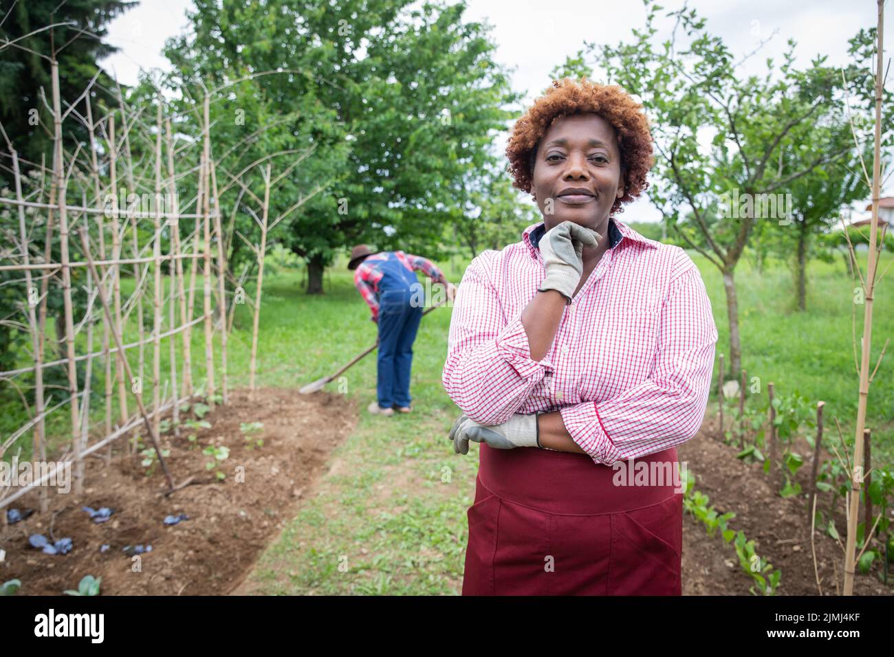 Porträt einer bäuerlichen Frau auf ihrem kultivierten Feld gräbt ihr Mann die Erde, ein Kleinunternehmer. Stockfoto