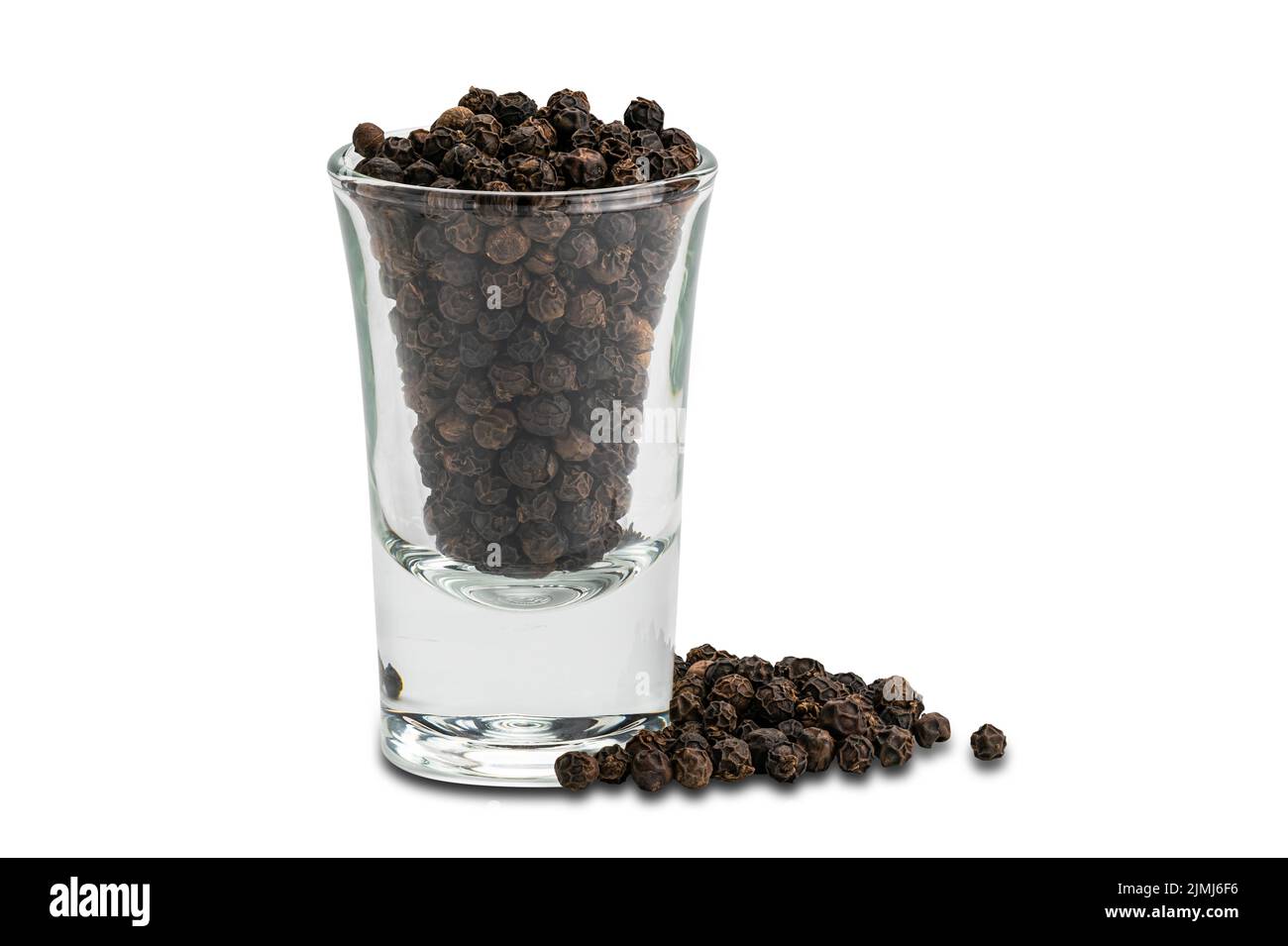 Seitenansicht Stapel von schwarzen Pfeffersamen und schwarzen Paprika Samen in kleinem Glas auf weißem Hintergrund. Stockfoto