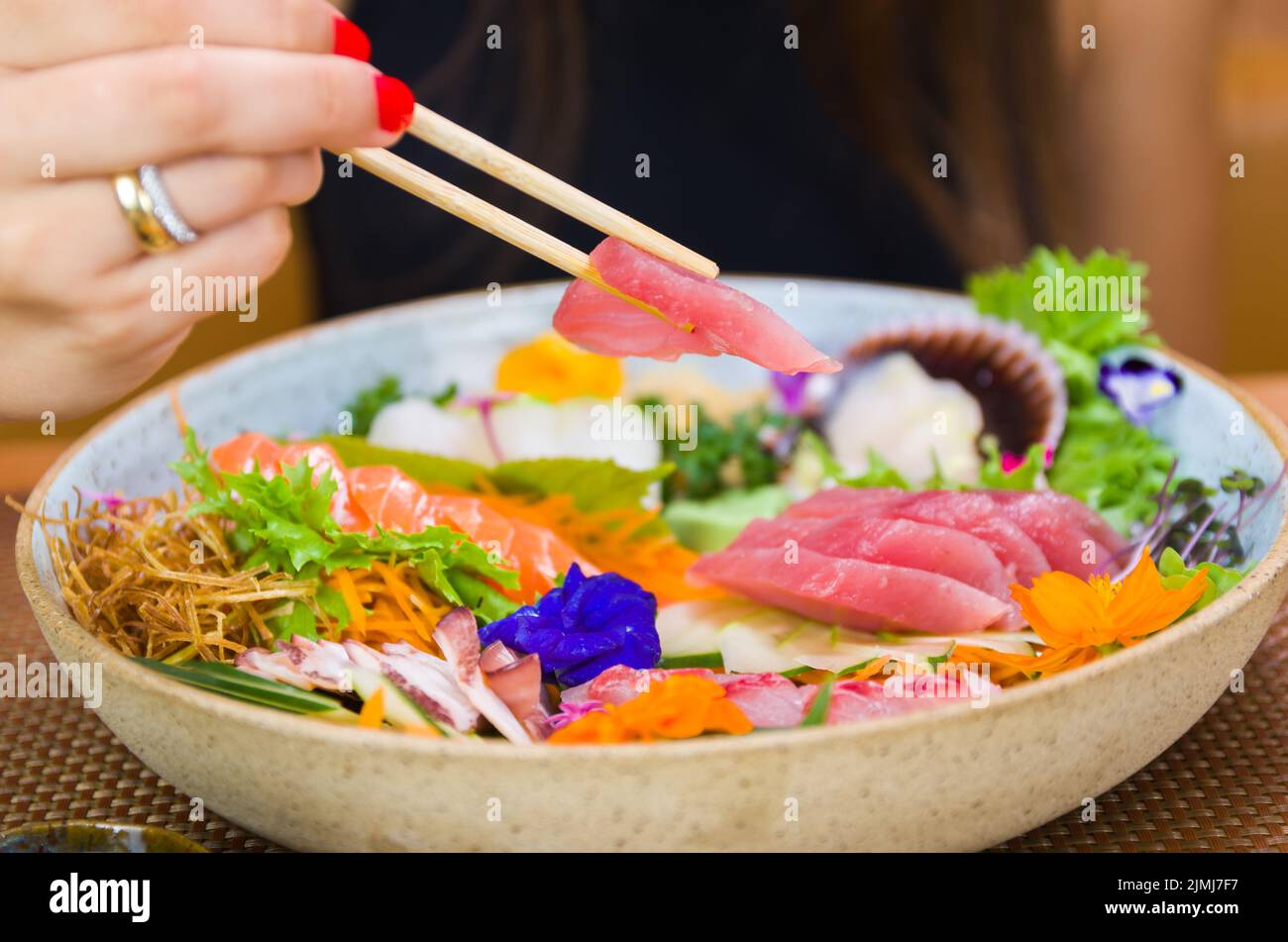 Frau, die köstliche Sashimi isst, Nahaufnahme von Essstäbchen. Stockfoto