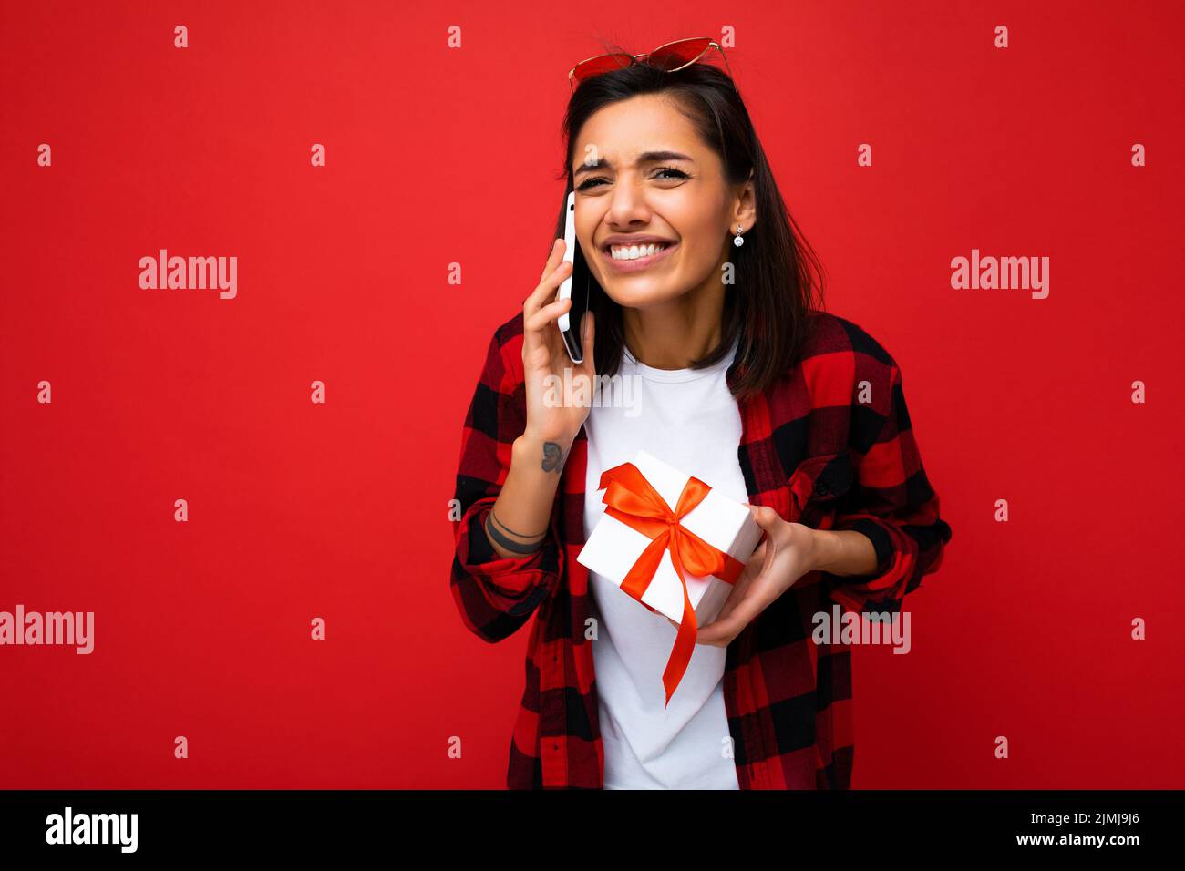 Shot von schönen glücklich emotionale junge Brünette Frau isoliert über roten Hintergrund Wand tragen weiße casual T-Shirt und rot ein Stockfoto