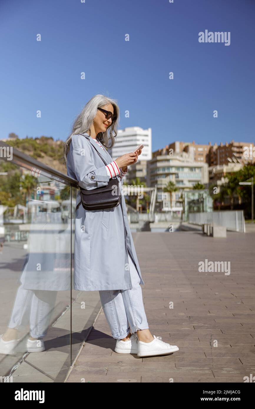 Foto von charmanten Frau mit Smartphone in der Stadt Stockfoto