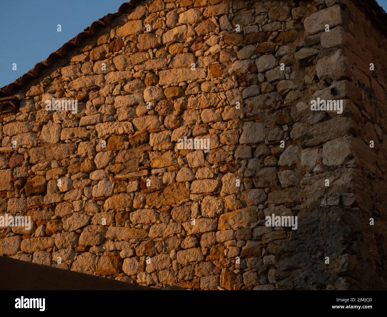 Steinmauer bei Sonnenuntergang. Konzept einer nachhaltigen Architektur Stockfoto