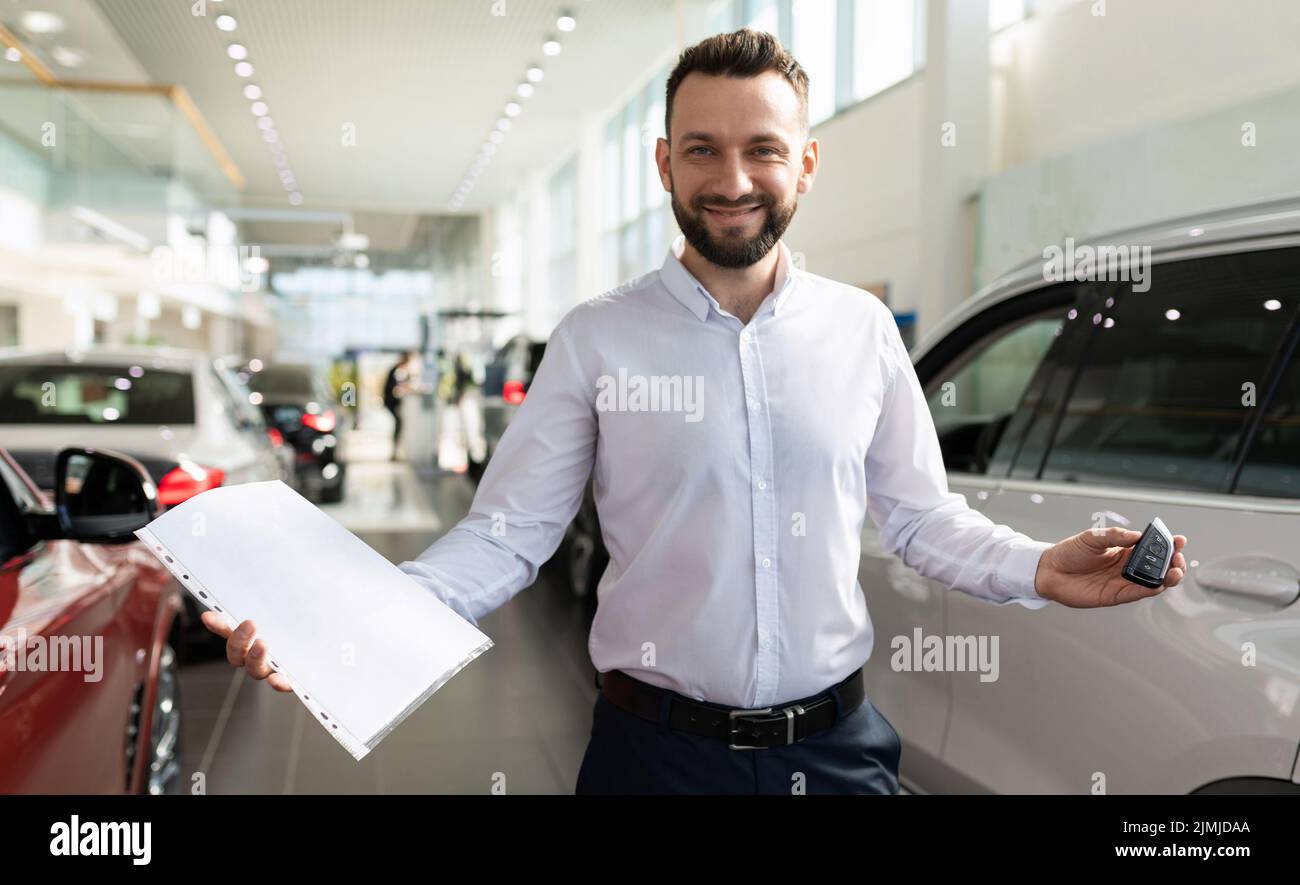 Der Besitzer eines Neuwagens in einem Händlerraum demonstriert Dokumente und Schlüssel eines Neuwagens Stockfoto