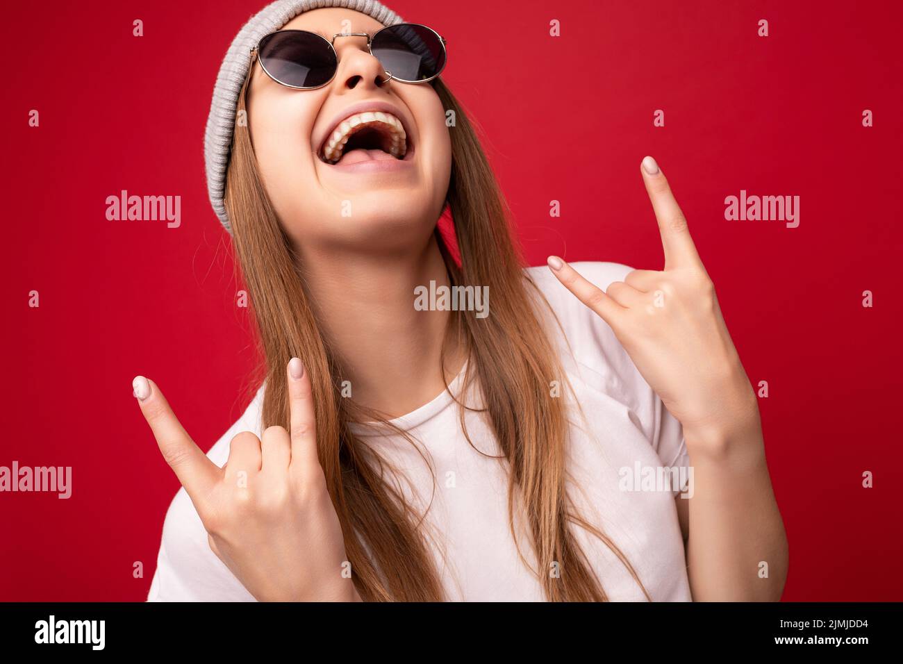 Nahaufnahme von jungen emotionalen positiv glücklich attraktive dunkelblonde Frau mit aufrichtigen Emotionen tragen lässiges weißes T-Shirt, grau Stockfoto