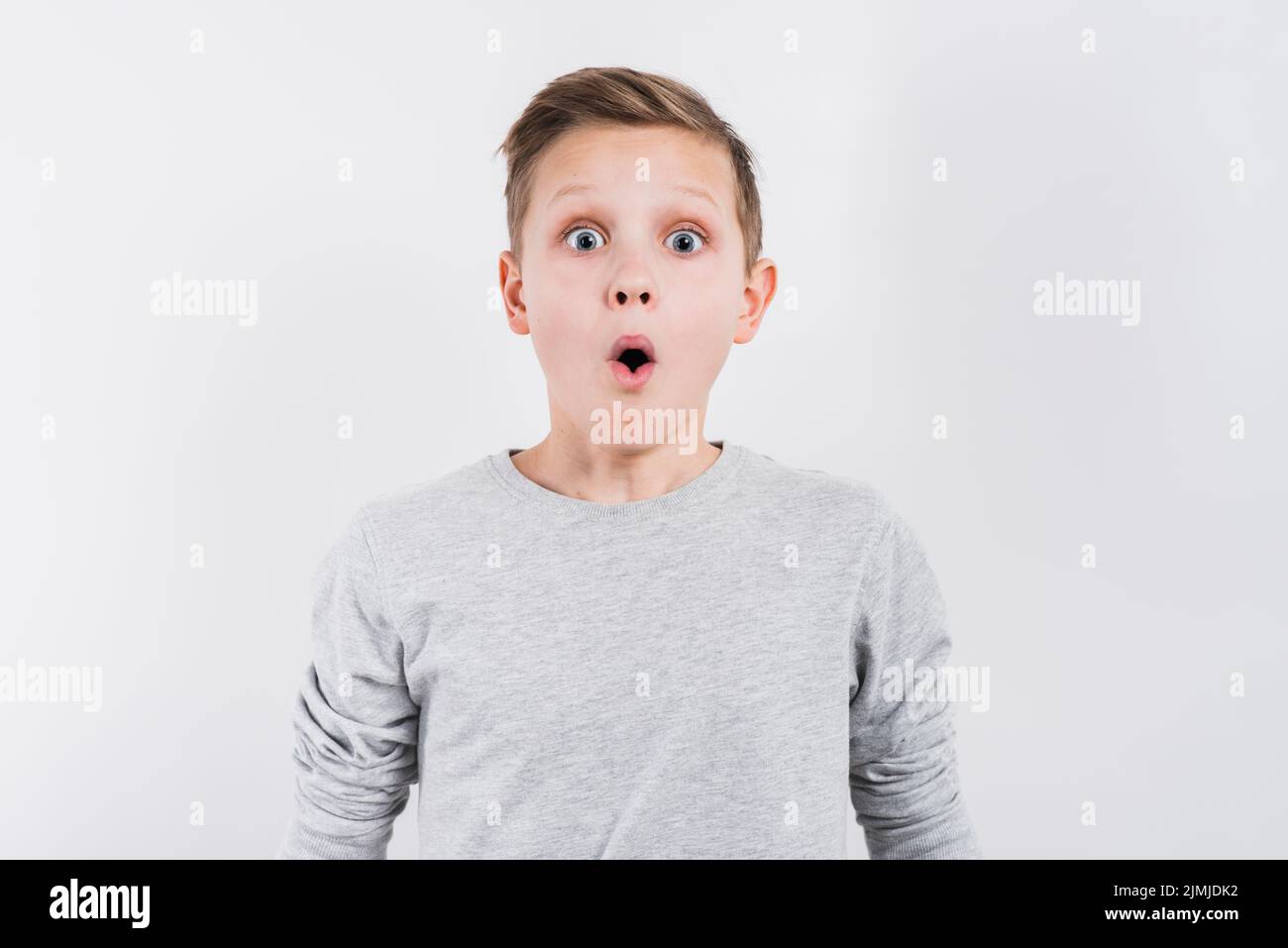 Schockiert Junge aussehende Kamera vor grauem Hintergrund Stockfoto