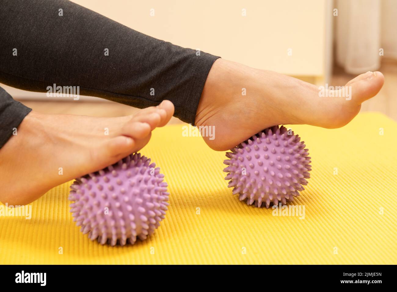 Weibliche Füße und lila stachelige Massagebälle Stockfoto