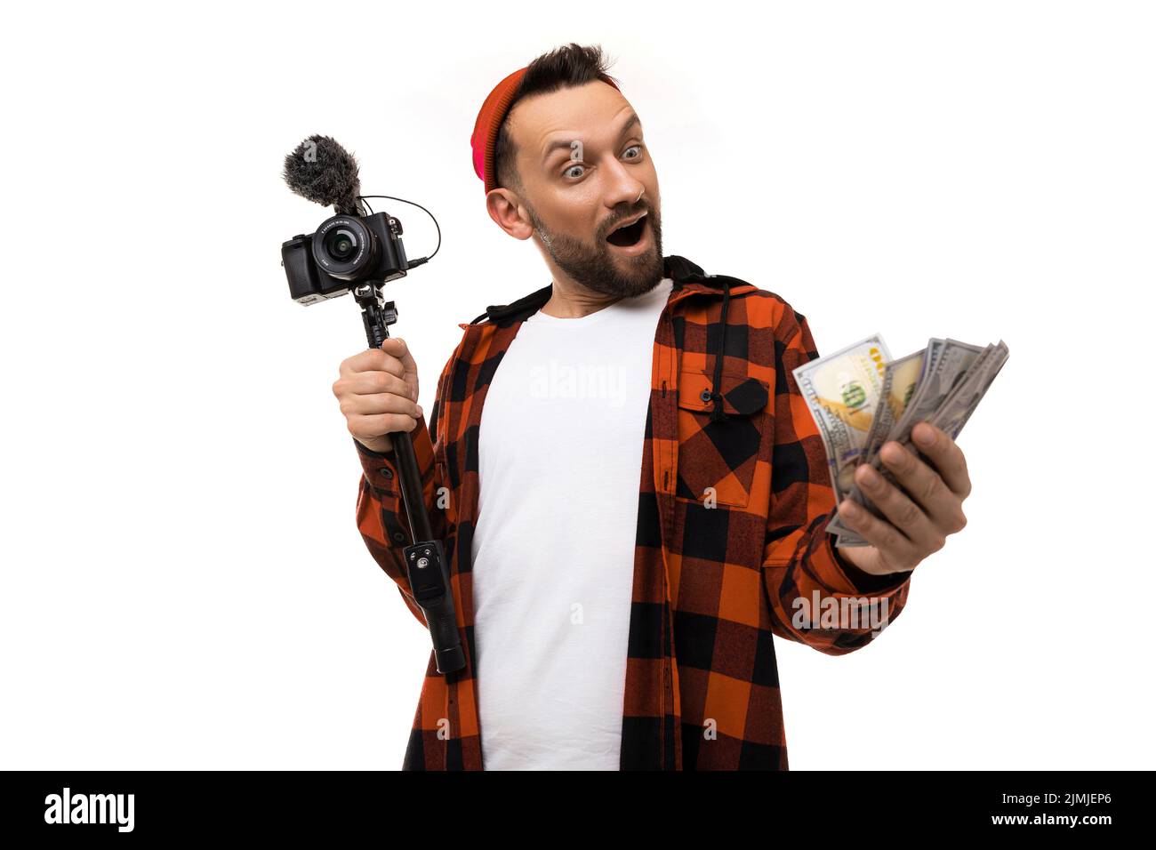 Junger Blogger mit einer Videokamera mit Mikrofon und Geld in den Händen auf weißem Hintergrund Stockfoto
