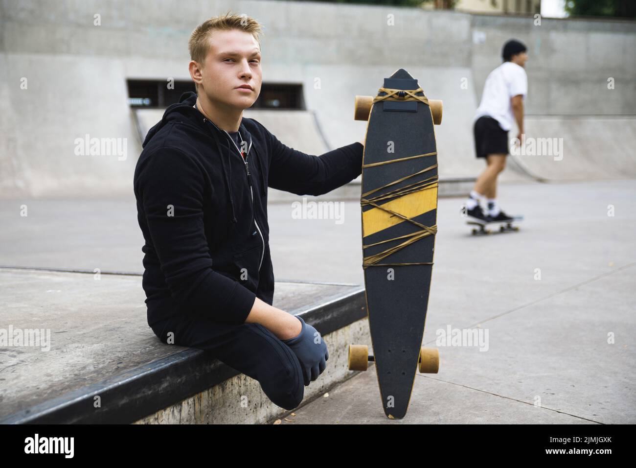 Motivierter Behinderter mit Longboard im Skatepark Stockfoto