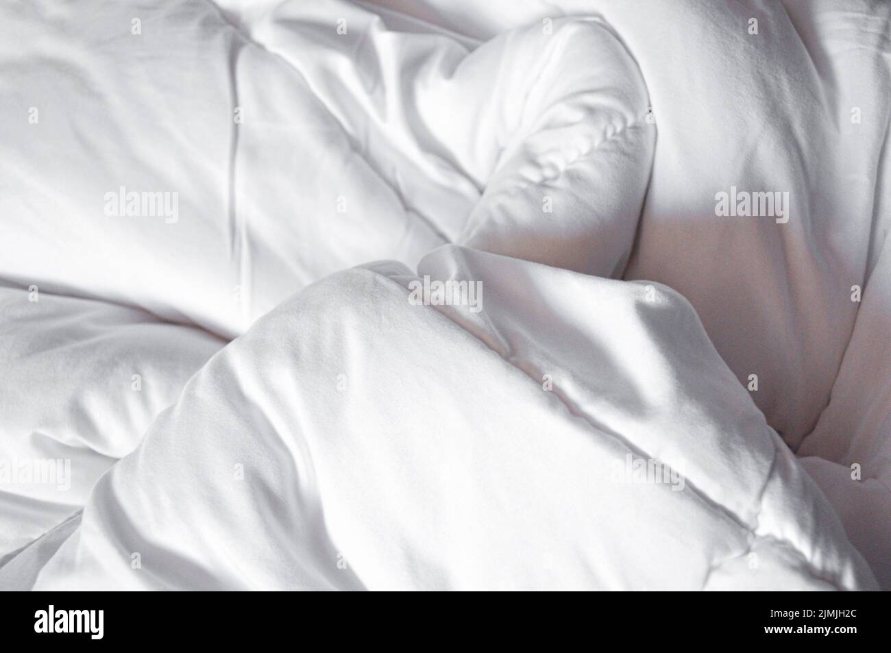 Weiße Decke. Knittern Sie die schmutzige Decke im Schlafzimmer nach dem Aufwachen am Morgen. Bettdetails. Bettdecke und Decke, ein ungeschmachtes Bett im Hotelzimmer Stockfoto