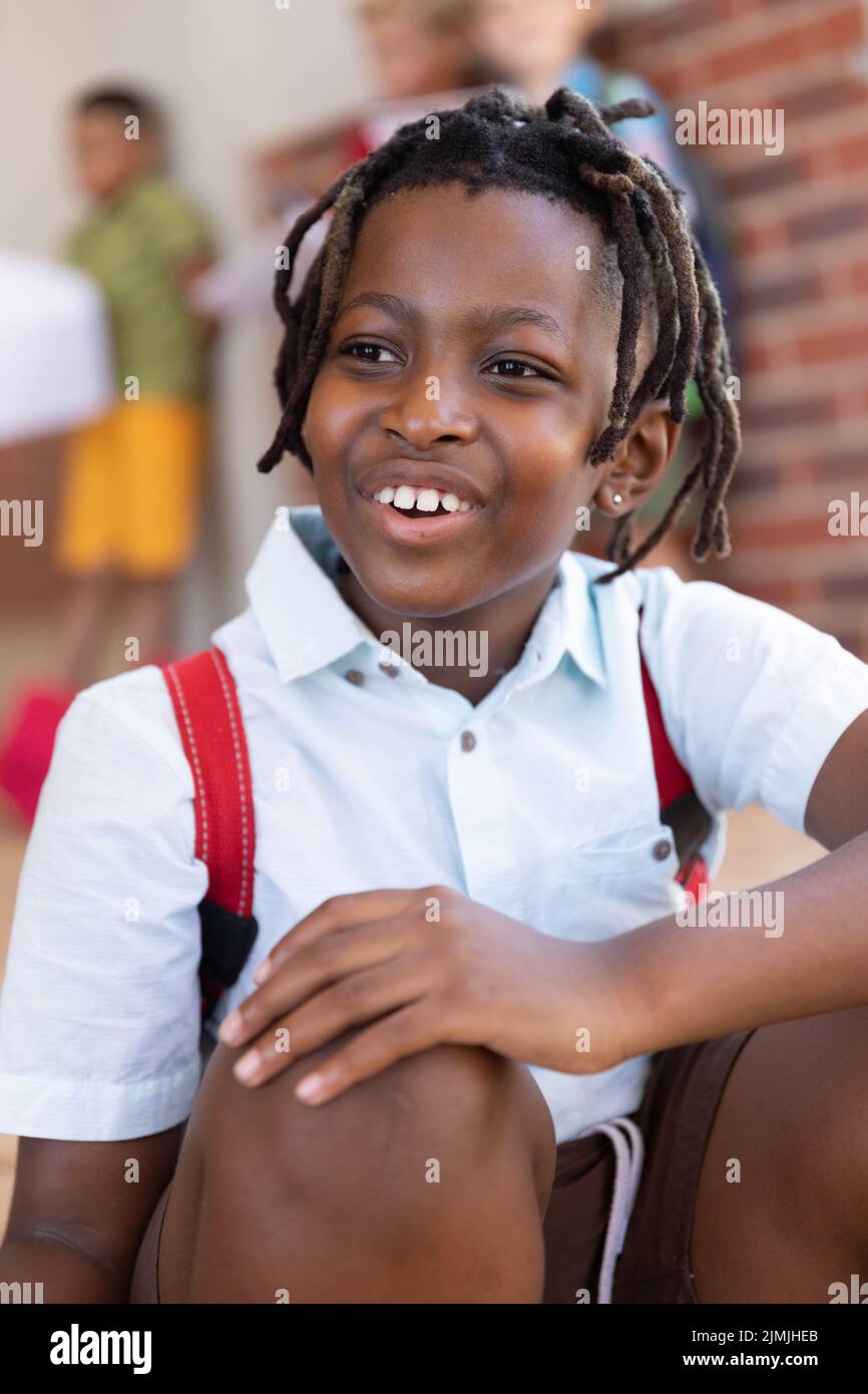 Nahaufnahme eines lächelnden afroamerikanischen Grundschuljungen mit Dreadlocks, die wegschauen Stockfoto