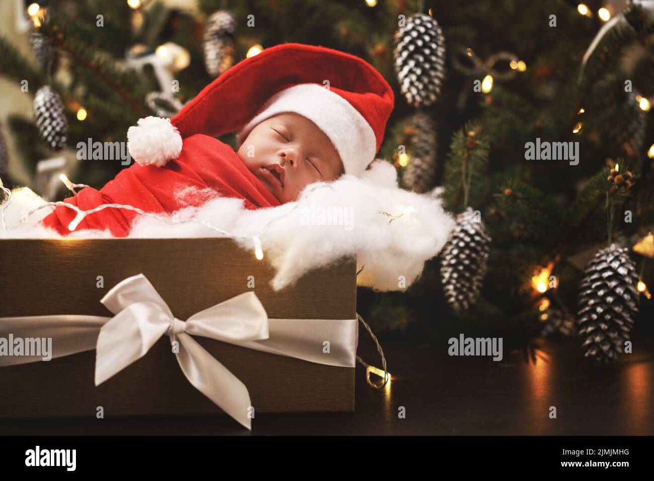 Niedliches neugeborenes Baby mit Weihnachtsmannhut schläft in der Weihnachts-Geschenkbox Stockfoto