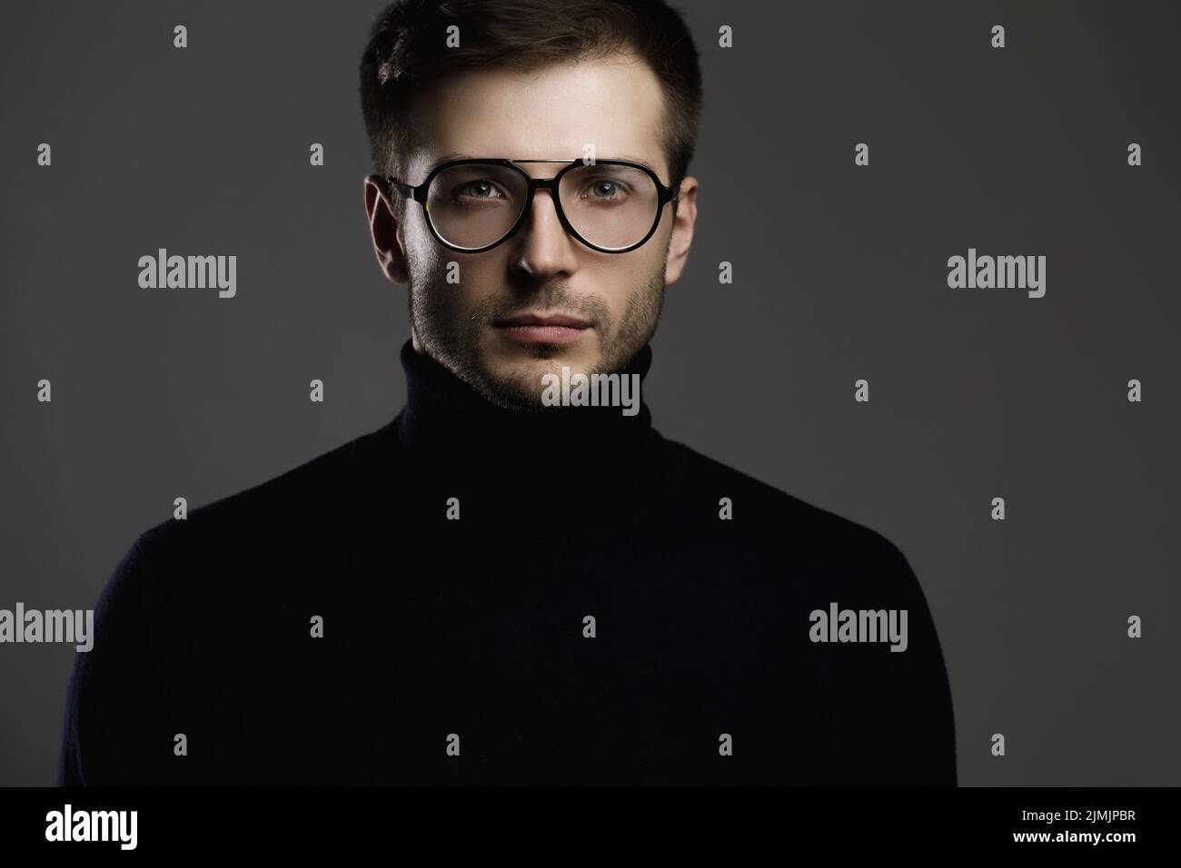 Junger, eleganter Mann mit Brille und einem gefalteten Polokragen Stockfoto
