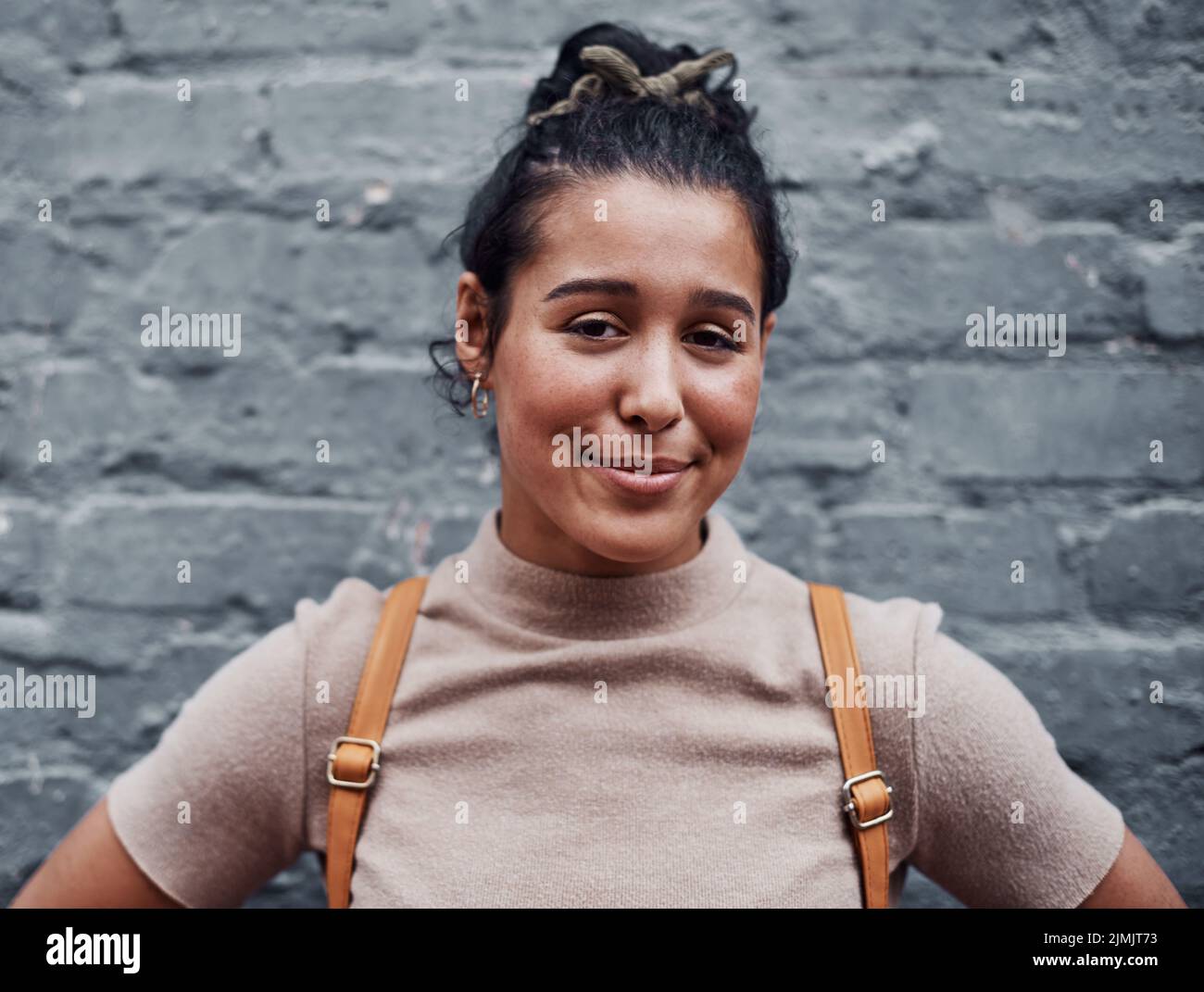 Selbstvertrauen macht sie schön. Beschnittenes Porträt eines attraktiven Teenagers, das allein gegen eine graue Wand in der Stadt steht. Stockfoto