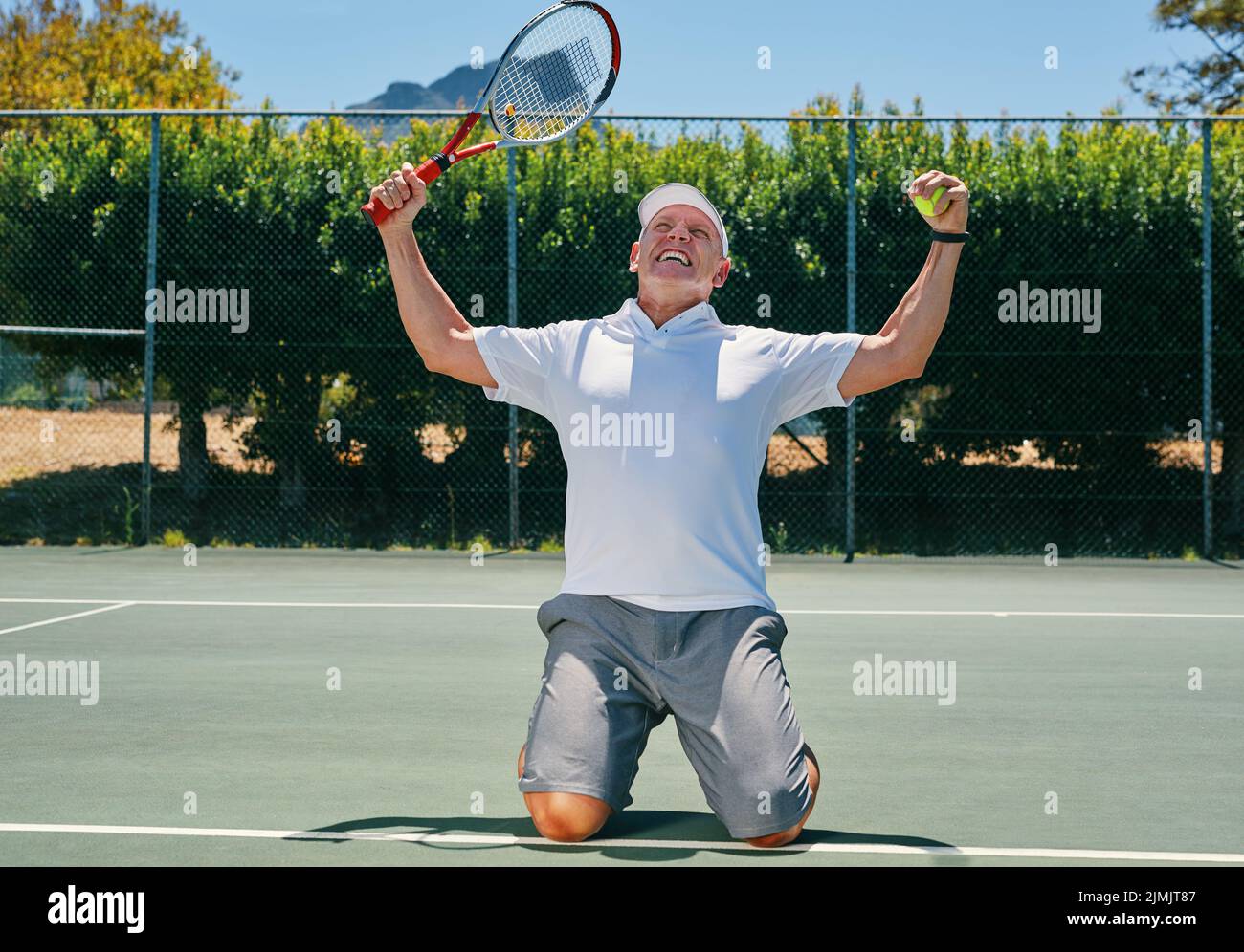 Ich bin der Mann. Ein hübscher reifer Mann, der einen Sieg feiert, während er tagsüber Tennis spielt. Stockfoto