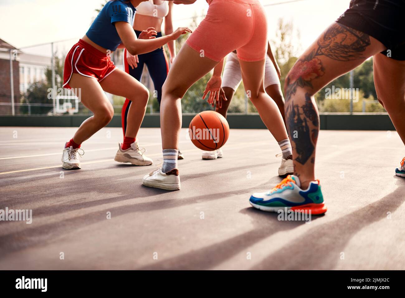 Wo die Hauptaktion ist. Eine vielfältige Gruppe von Sportlerinnen spielen ein Wettkampfspiel des Basketballs zusammen während des Tages. Stockfoto