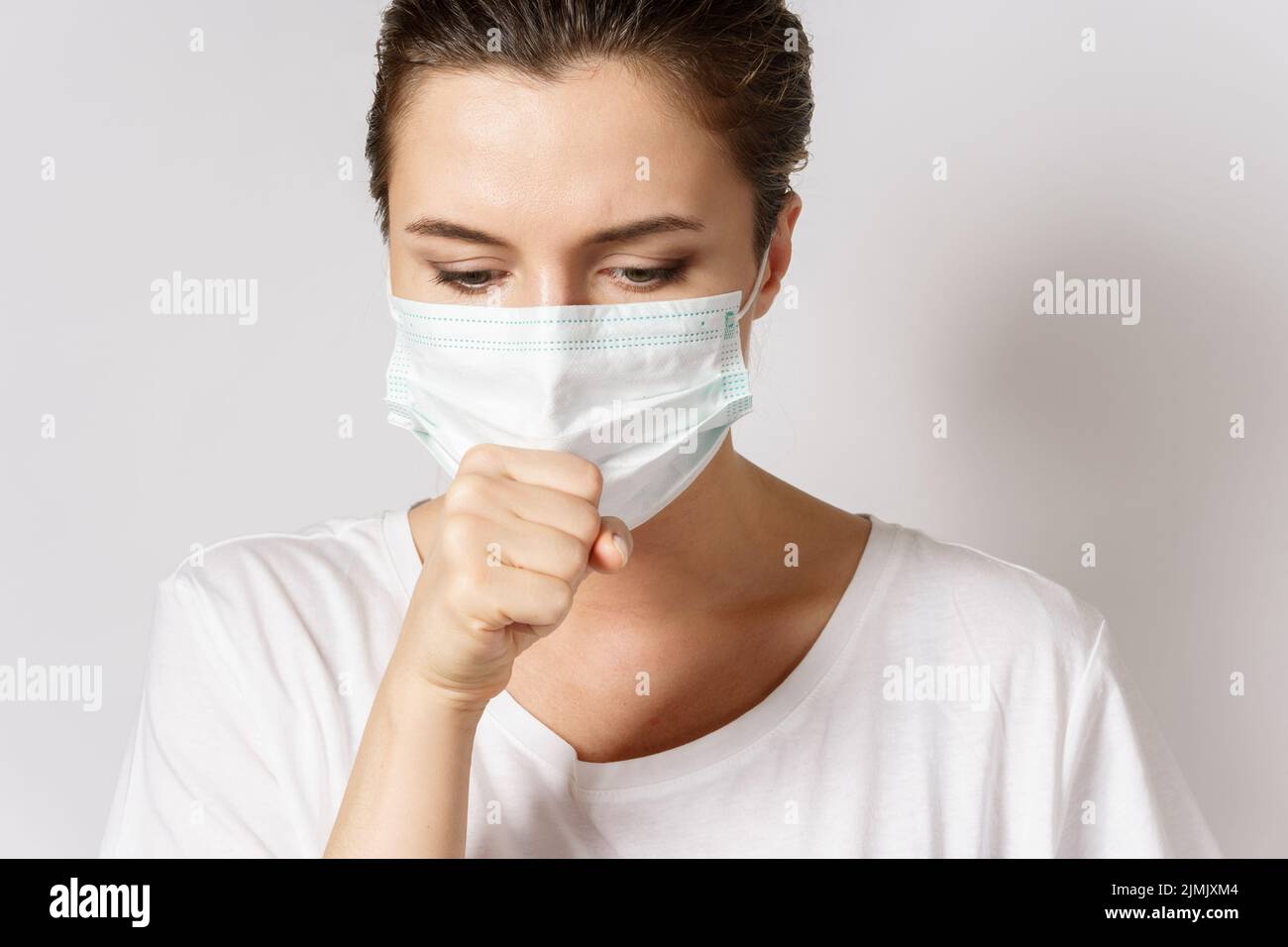 Die junge Frau trägt zum Schutz vor Viren eine Gesichtsmaske Stockfoto