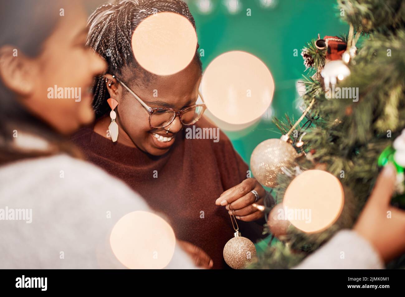 Die festliche Jahreszeit ist offiziell eröffnet. Zwei junge Frauen schmücken zu Hause einen Weihnachtsbaum. Stockfoto