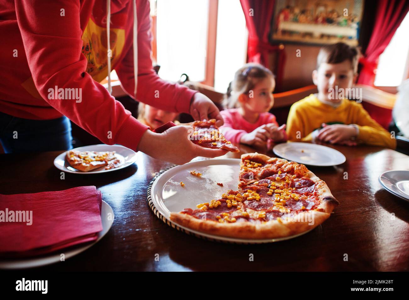Kinder sitzen an Geburtstagen am Tisch und essen Pizza. Stockfoto