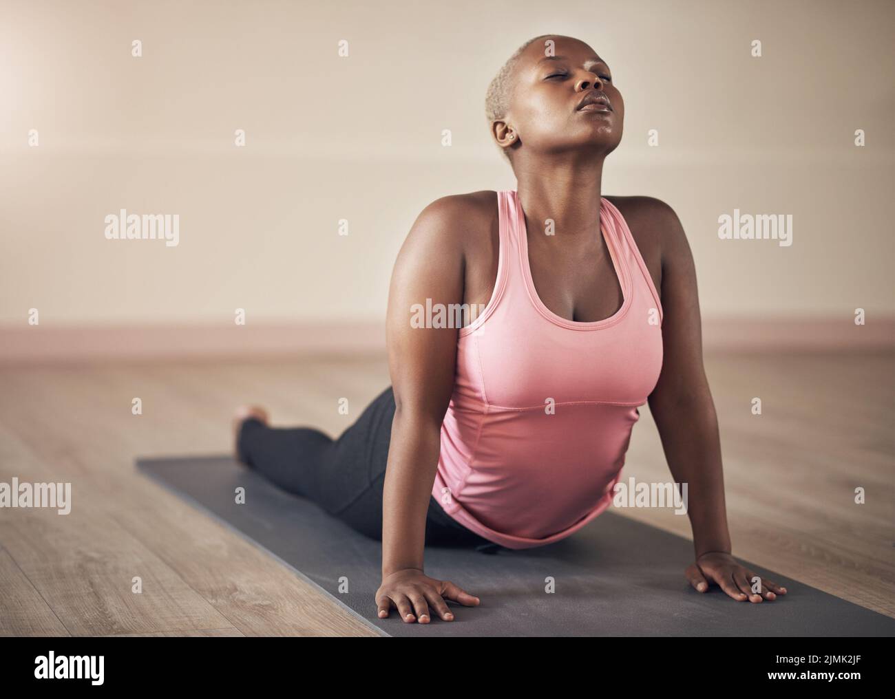 Ich kümmere mich um meinen Rücken. Eine attraktive junge Frau, die einen nach oben schauenden Hund allein während einer Yoga-Sitzung in der Halle hält. Stockfoto