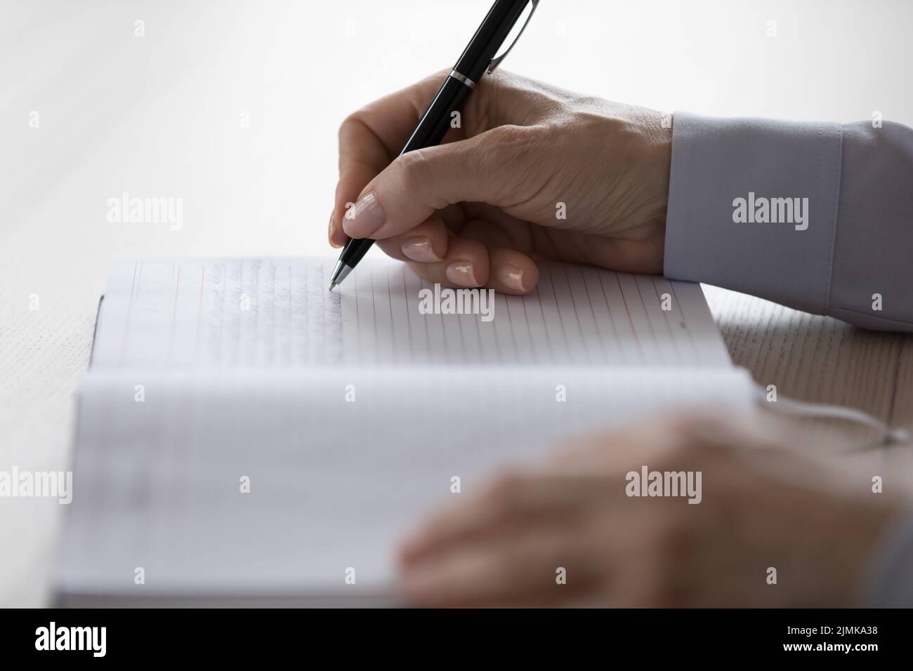 Hände einer erwachsenen Frau, die Notizen in einem Notizbuch schreibt Stockfoto
