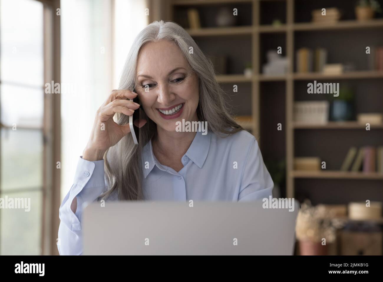 Fröhliche ältere reife freiberufliche Mitarbeiterin Frau im Gespräch auf dem Smartphone Stockfoto