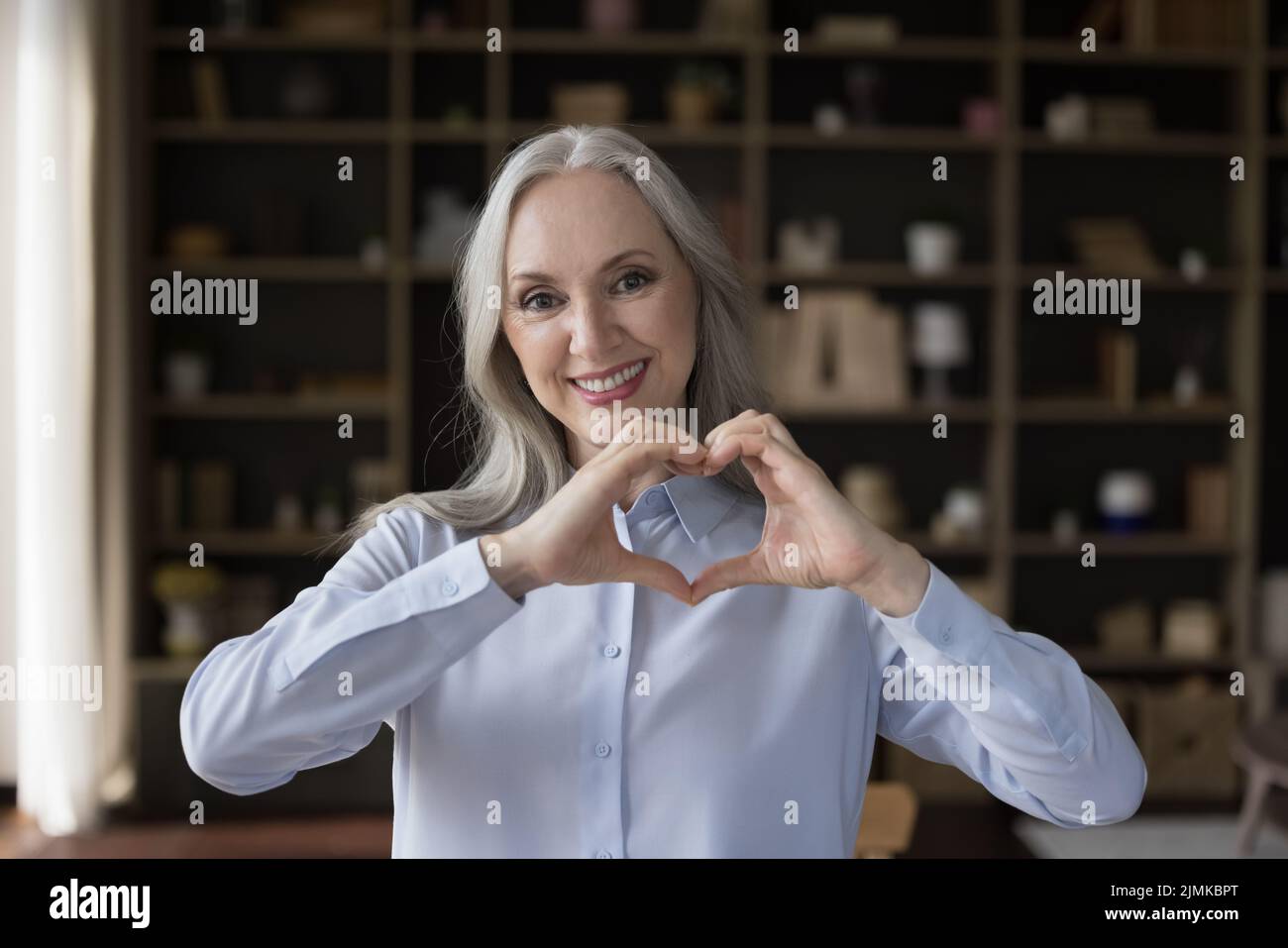 Glücklich attraktive ältere ältere Dame macht Finger Herz geformte Hände Stockfoto
