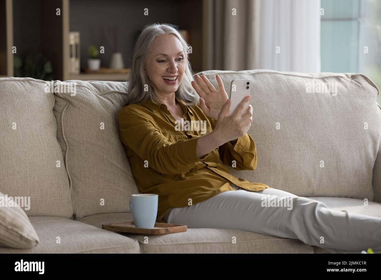 Happy Joyful ziemlich zieht Handy-Nutzer Frau winkt Hand hallo Stockfoto