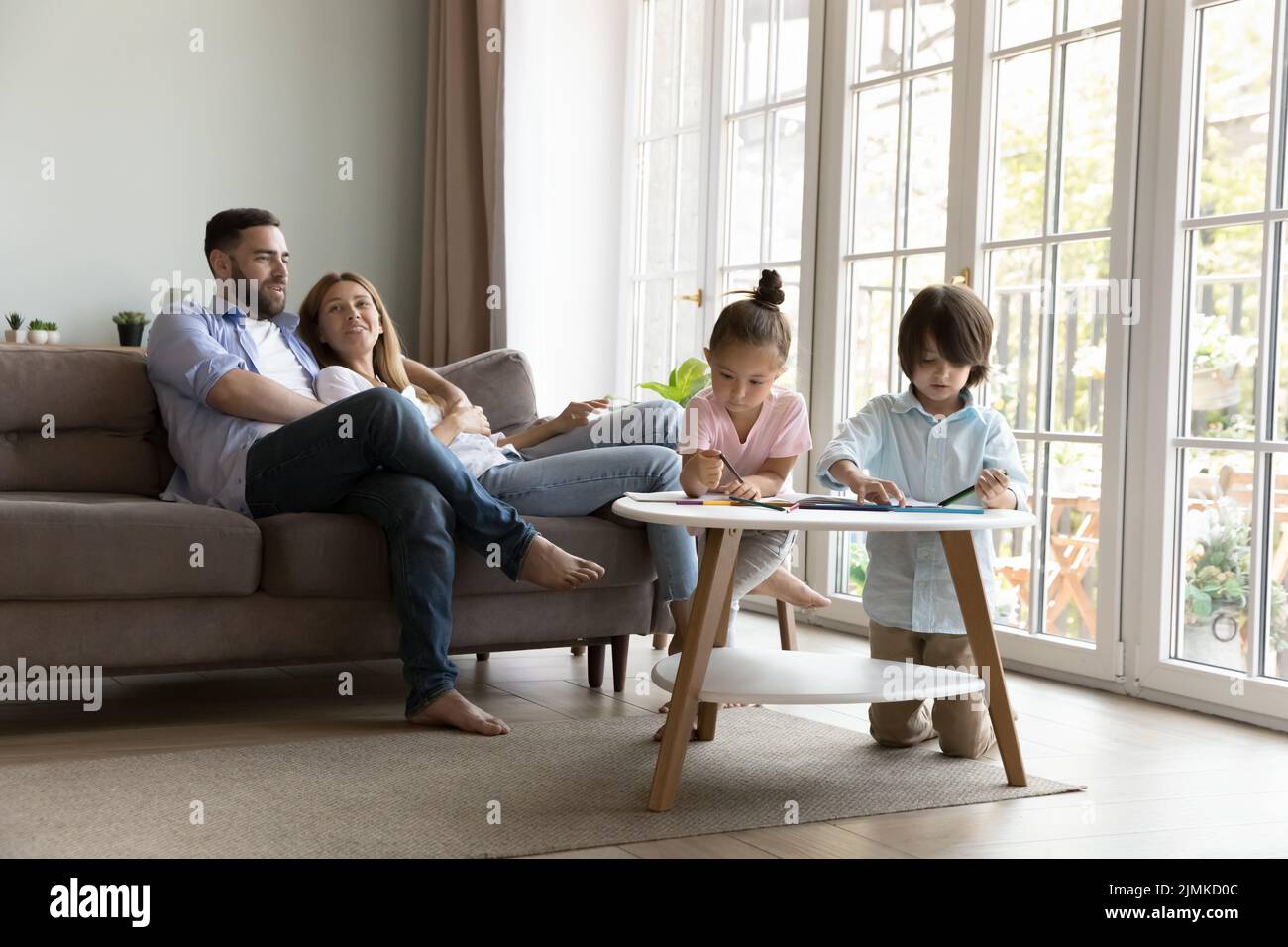 Paar auf dem Sofa ruhen ihre Kinder zeichnen in Skizzenbuch Stockfoto