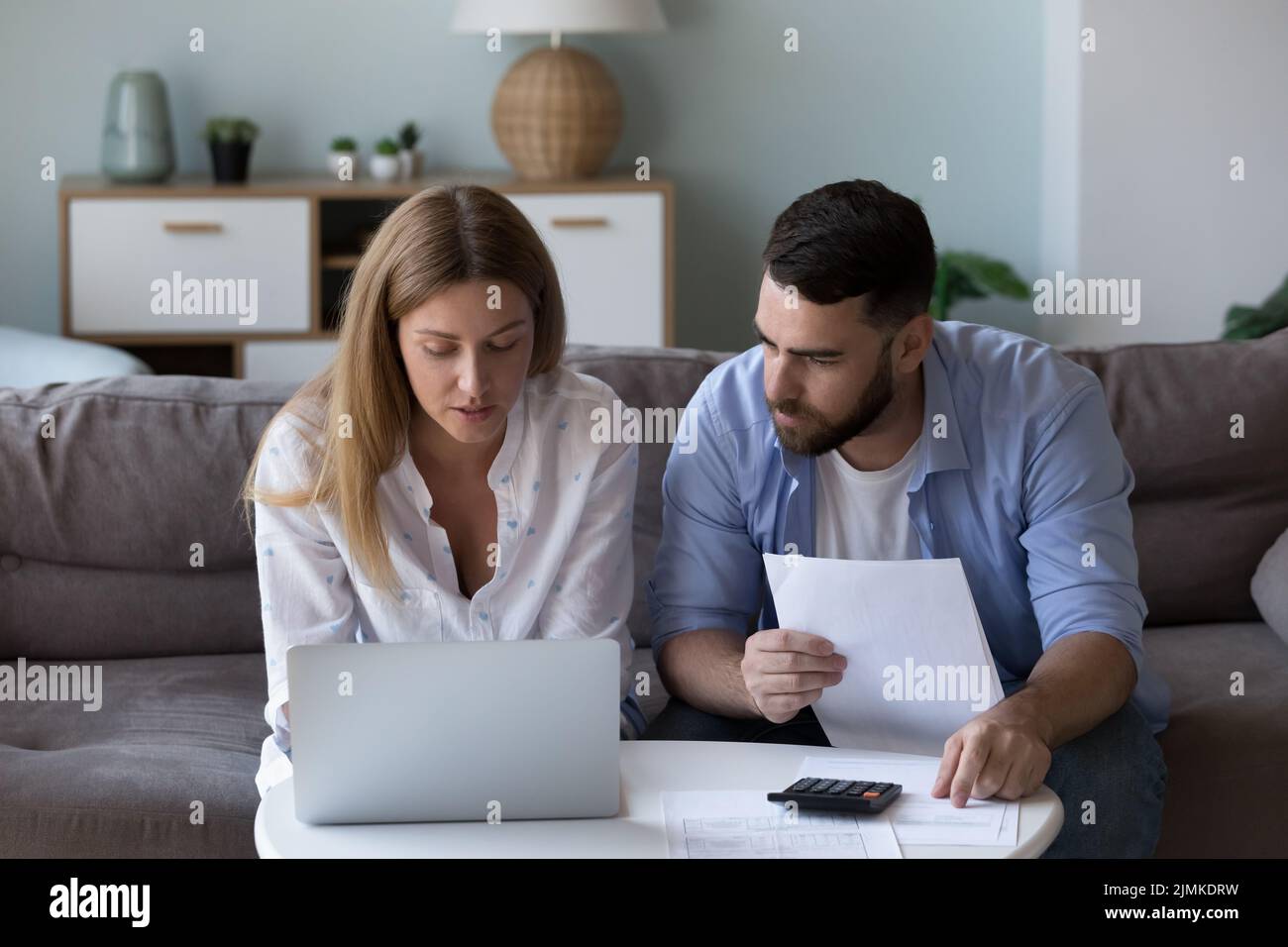 Seriöses, fokussiertes Millennial-Paar, das das Haushaltsbudget analysiert Stockfoto