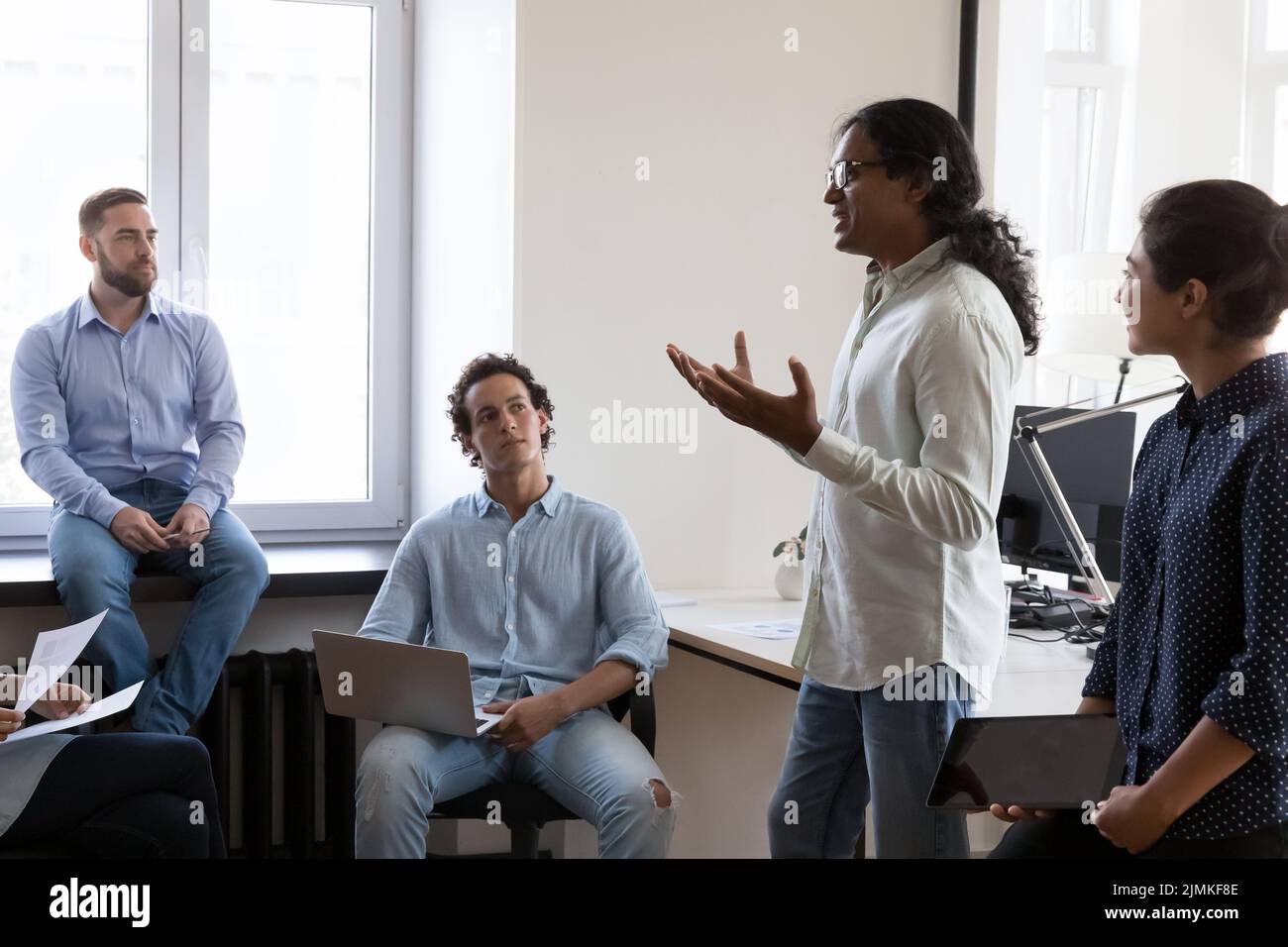 Die Mitarbeiter hören zu, wie der indische Firmenchef an einem Gruppentreffen teilnimmt Stockfoto